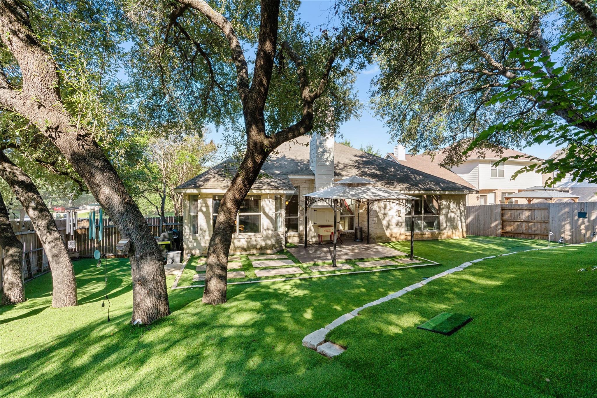 Mature trees shade a spacious green lawn behind t