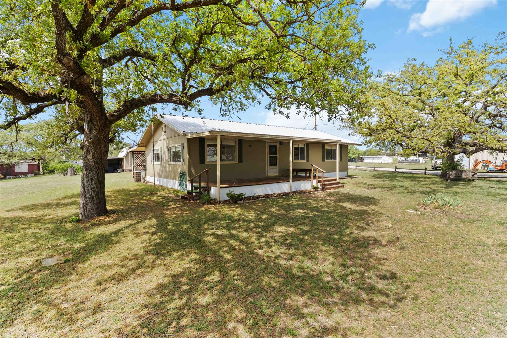 Back of property featuring a lawn, metal roof, fe