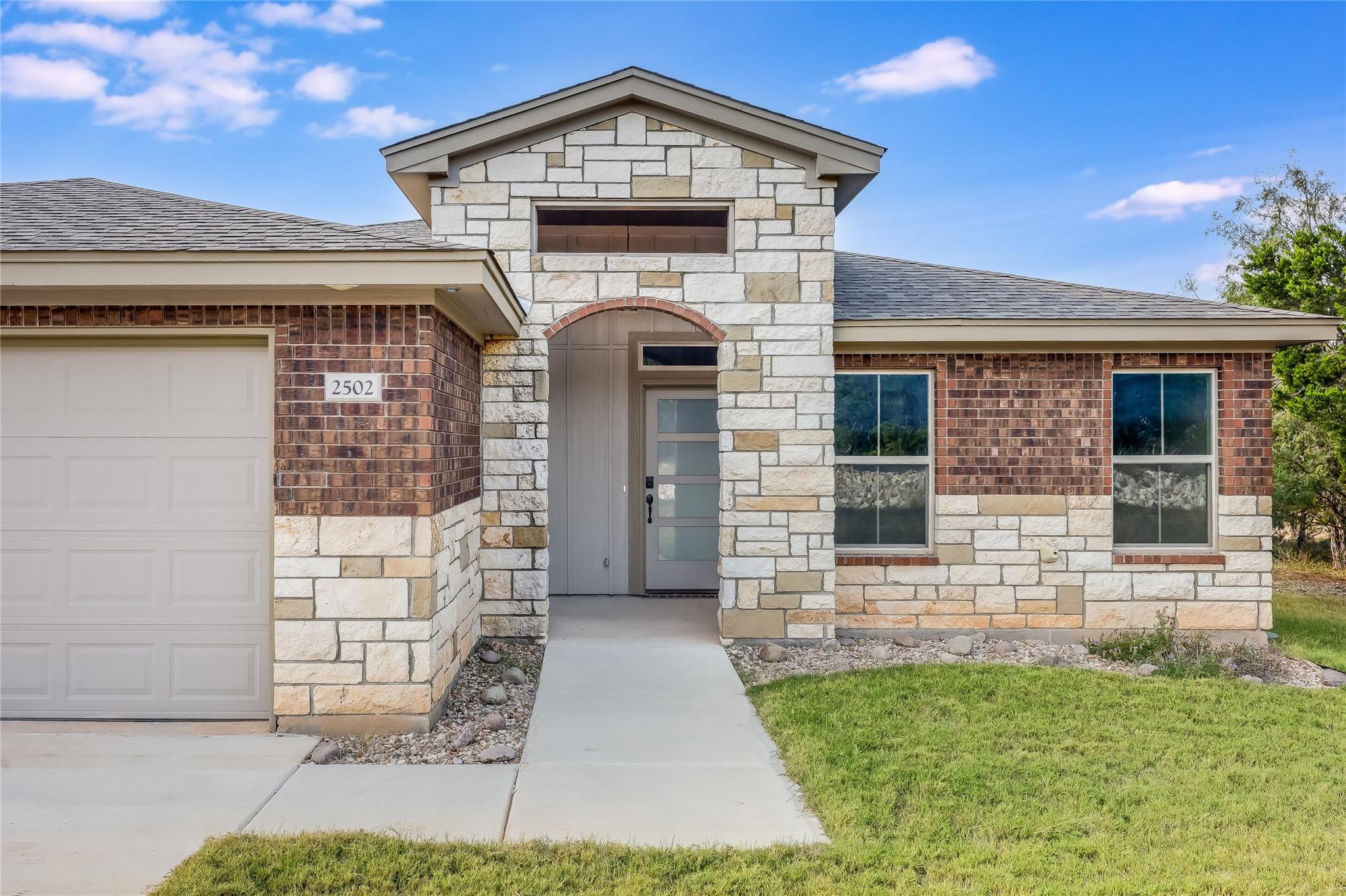 Entrance to property featuring stone siding, a ga
