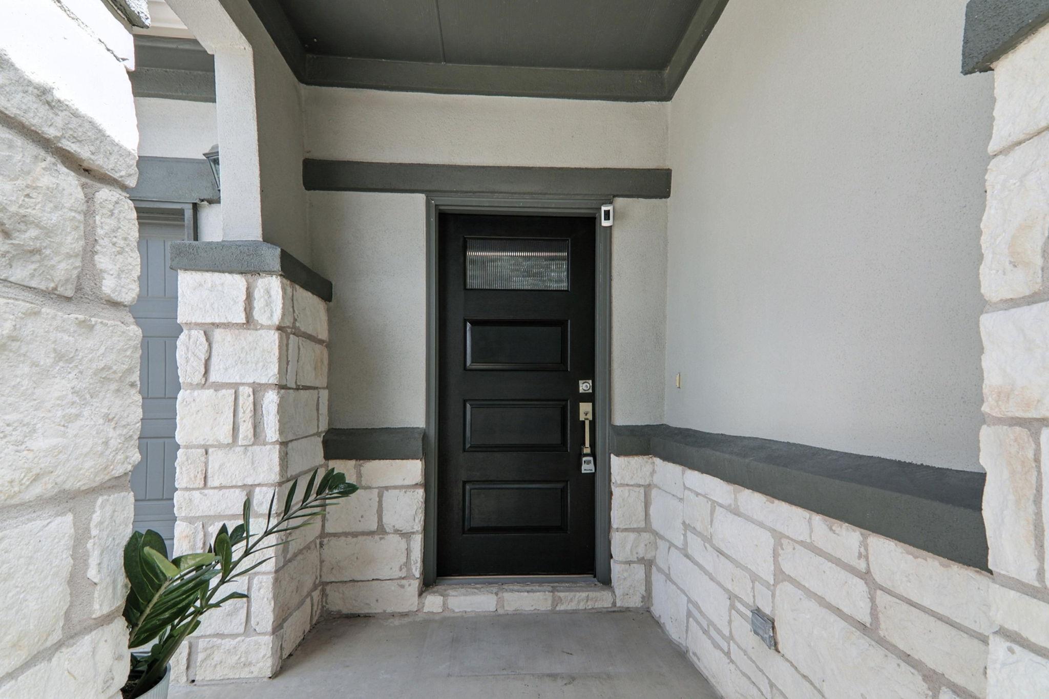 View of exterior entry with stone siding and stuc