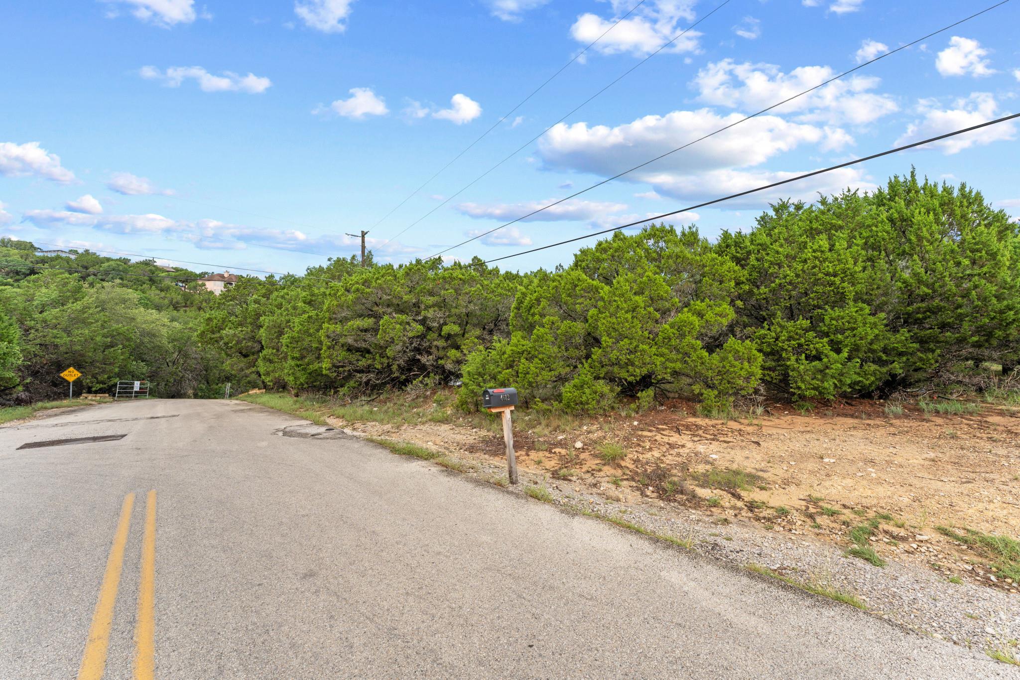 View of asphalt street featuring a wooded view