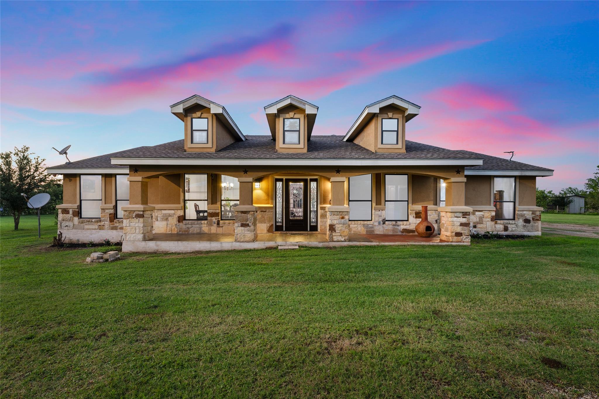 Rear view of property with stone siding and cover