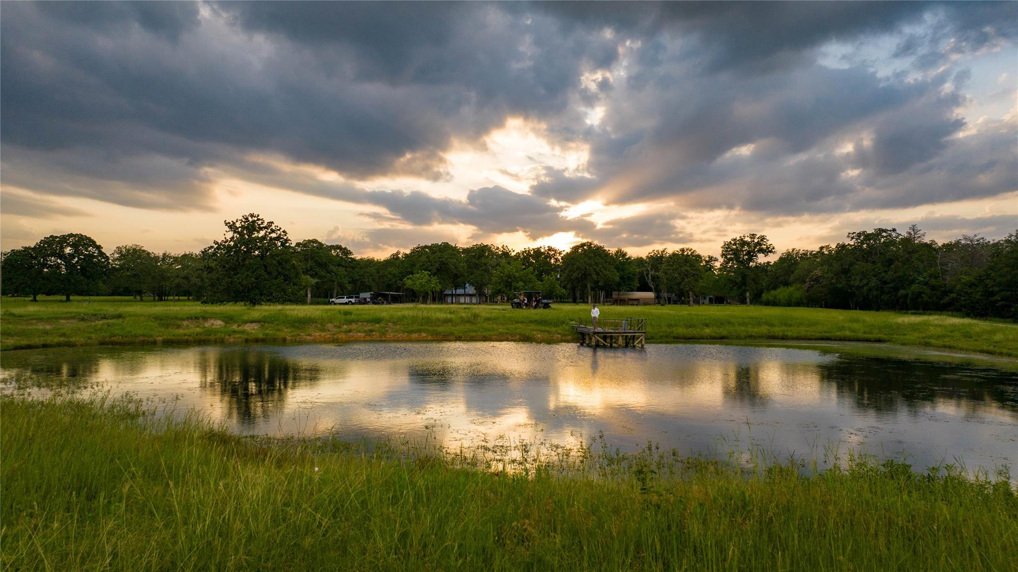 Reflecting sunset hues, a serene pond with a wood