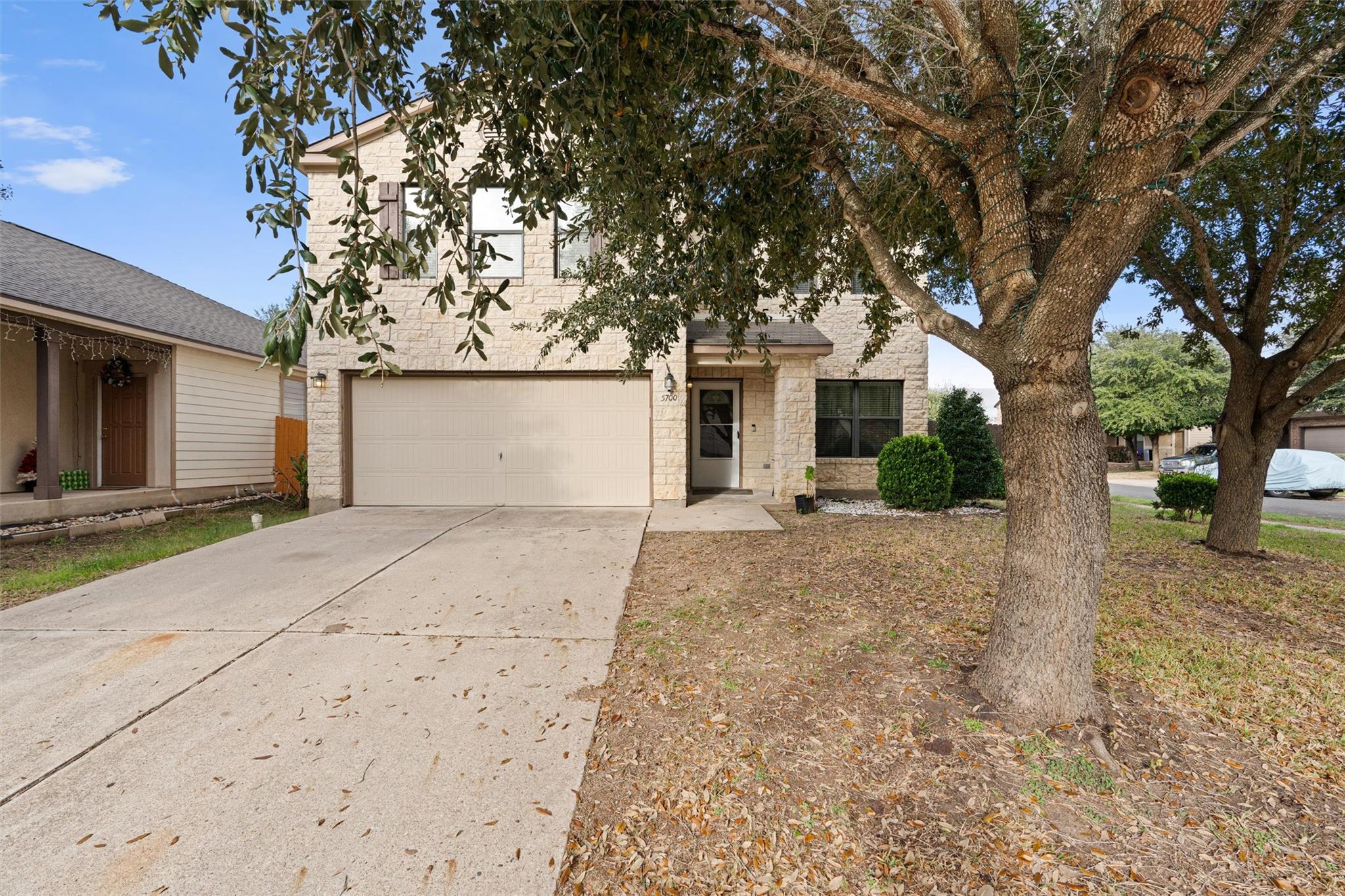 View of front facade with driveway, stone siding,