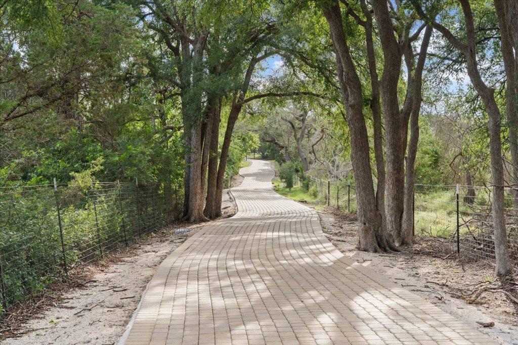 Shaded by mature trees, a long paver pathway wind