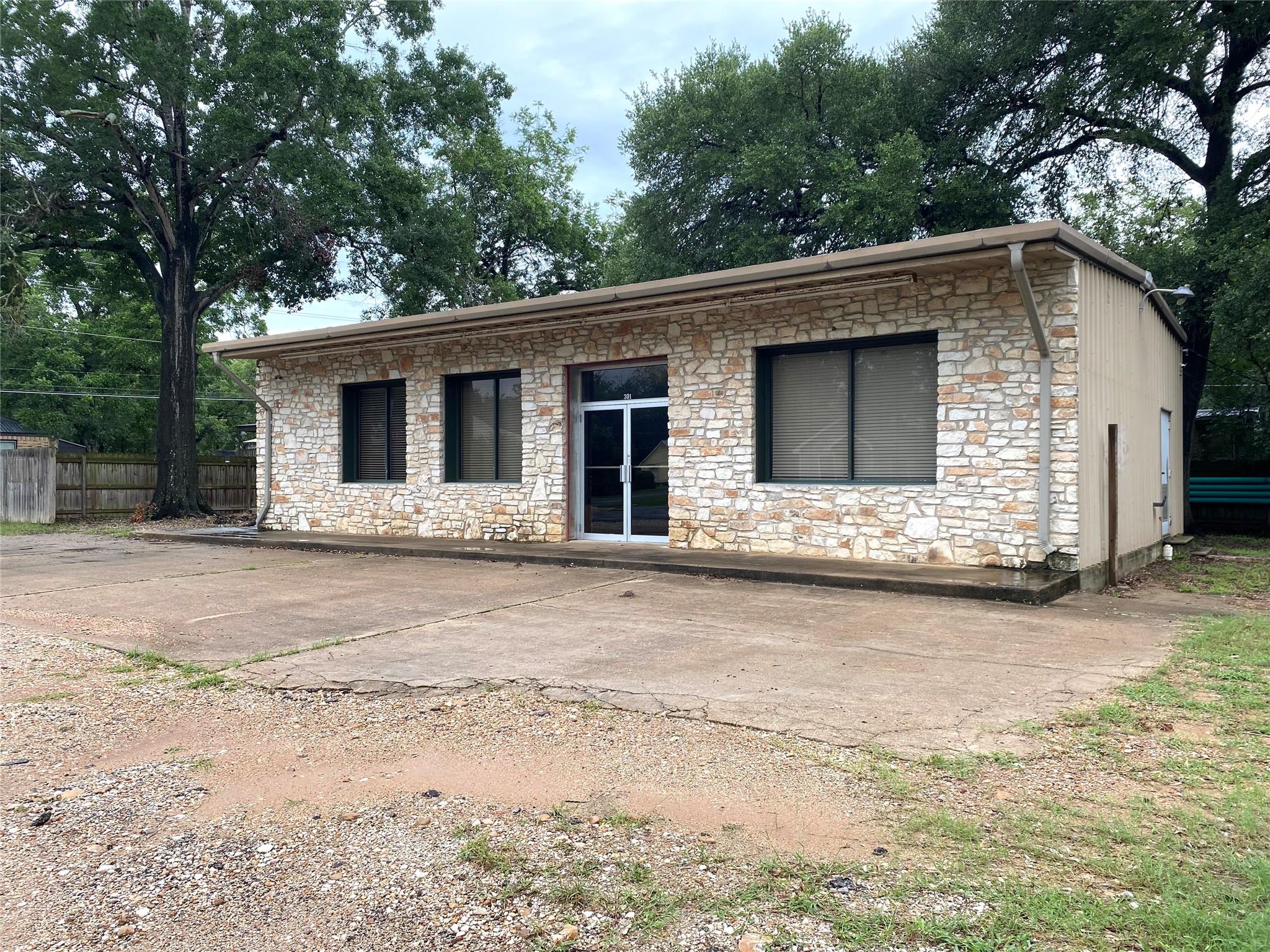 Back of property featuring stone siding and a pat