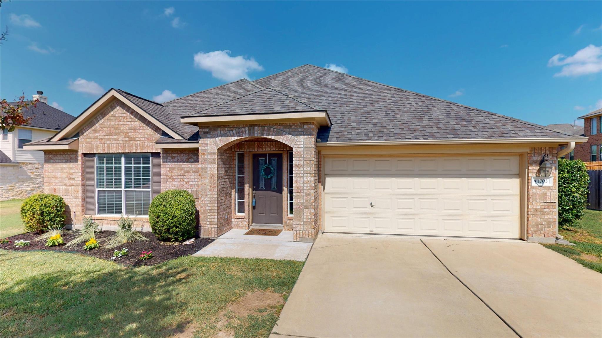 View of front of property with brick siding, a ga