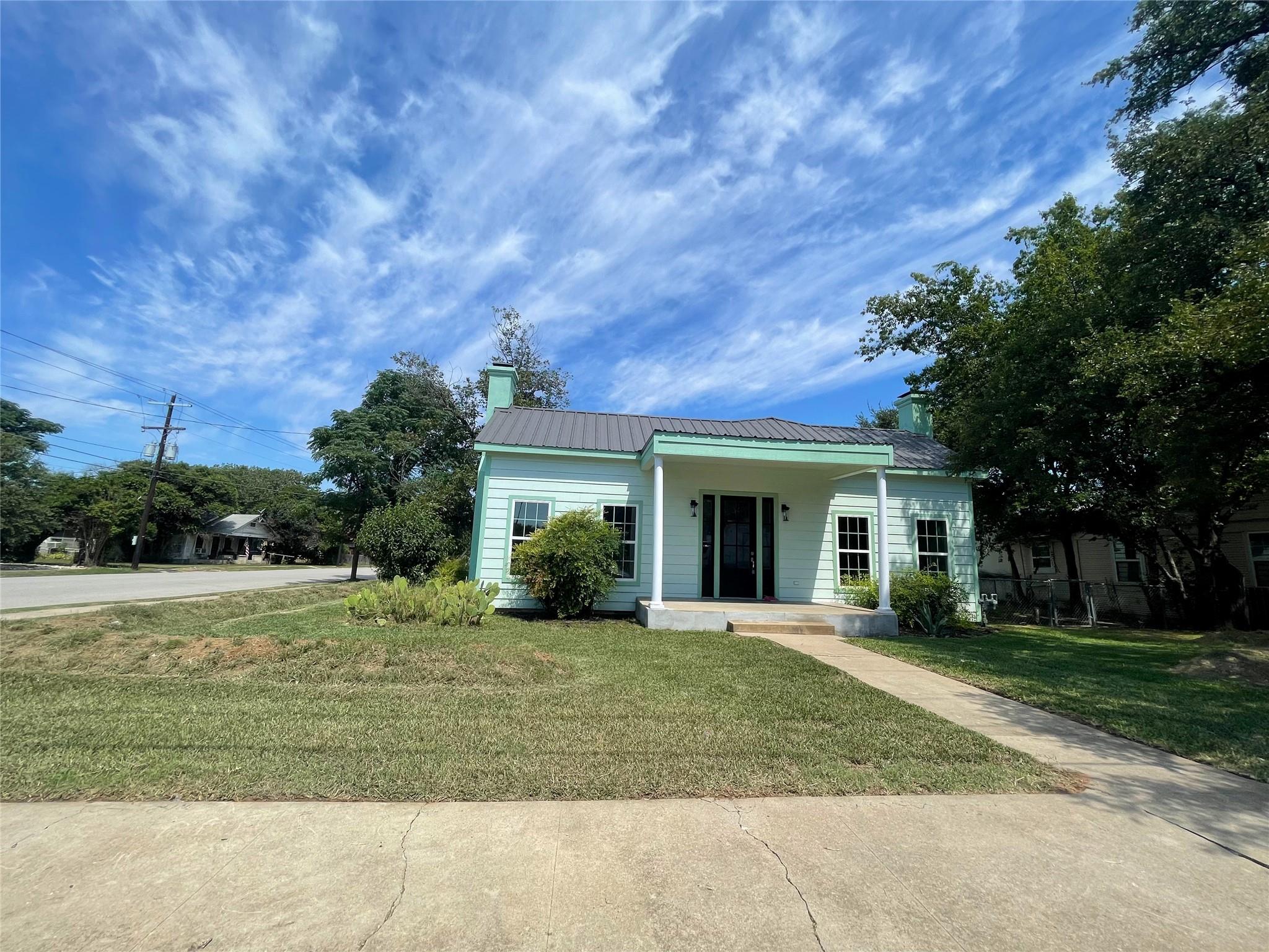 View of front of home with covered porch, a metal