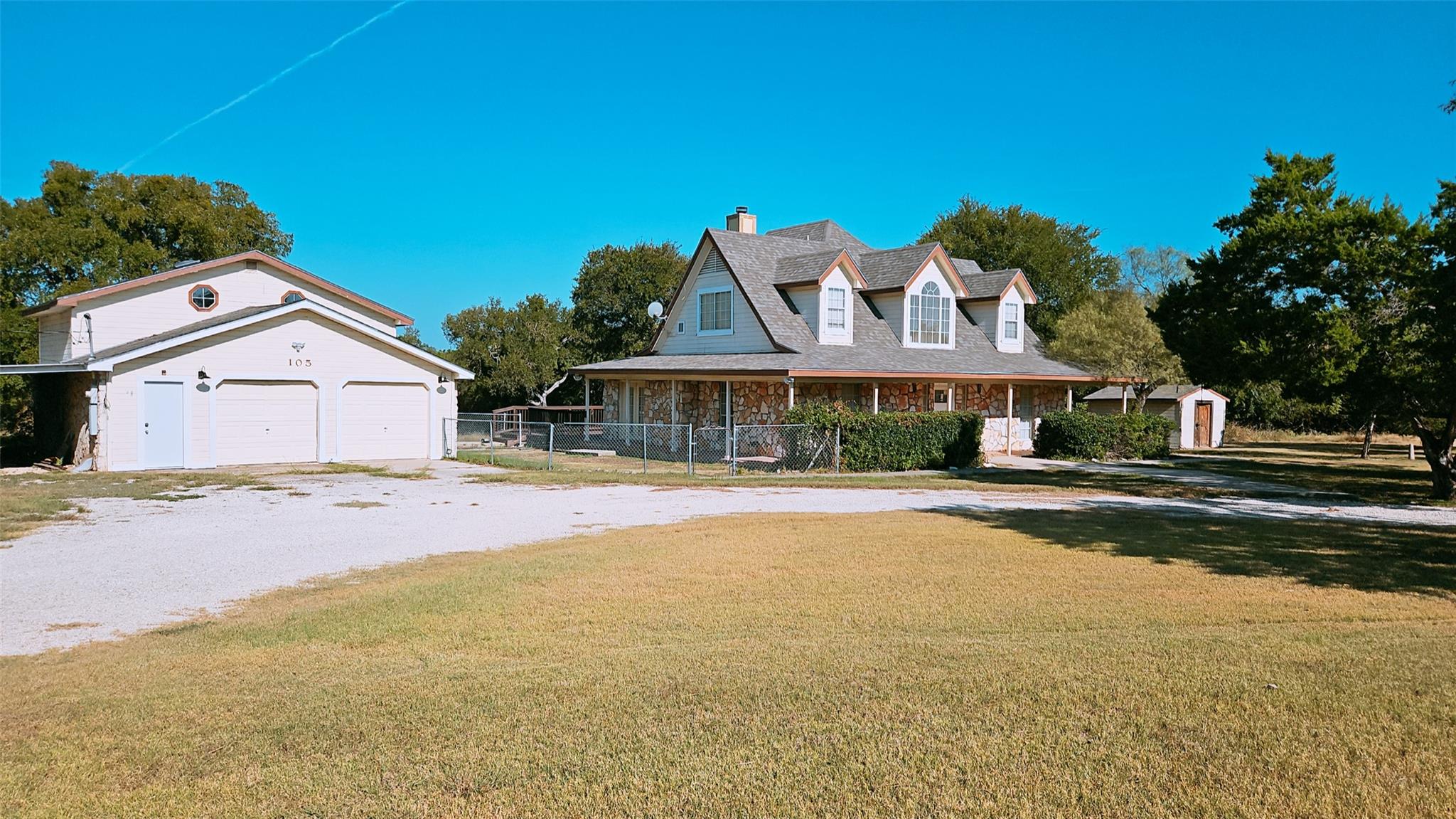 Farmhouse with covered porch, driveway, a garage,