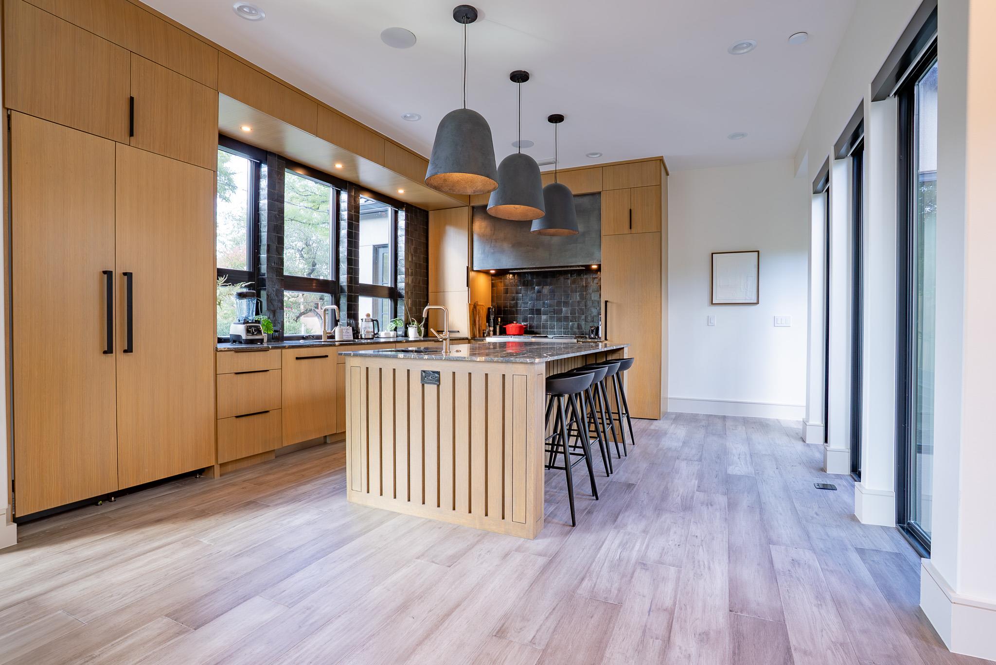 Kitchen with light wood finish cabinets, dark sto