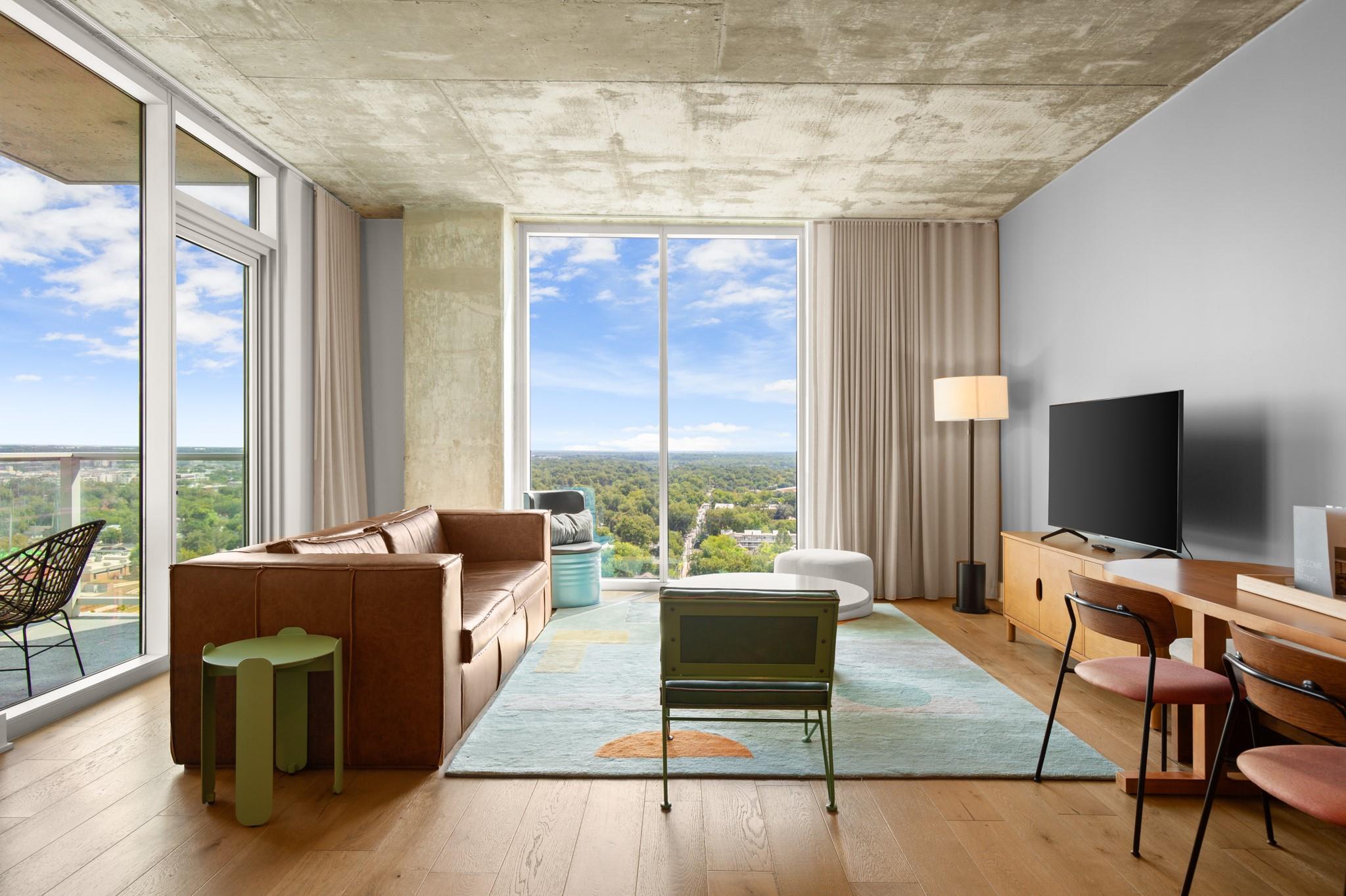 Living room with a wall of windows, light wood-ty