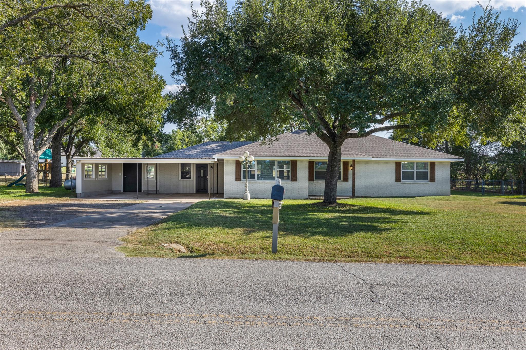 Ranch-style house featuring a front yard, asphalt