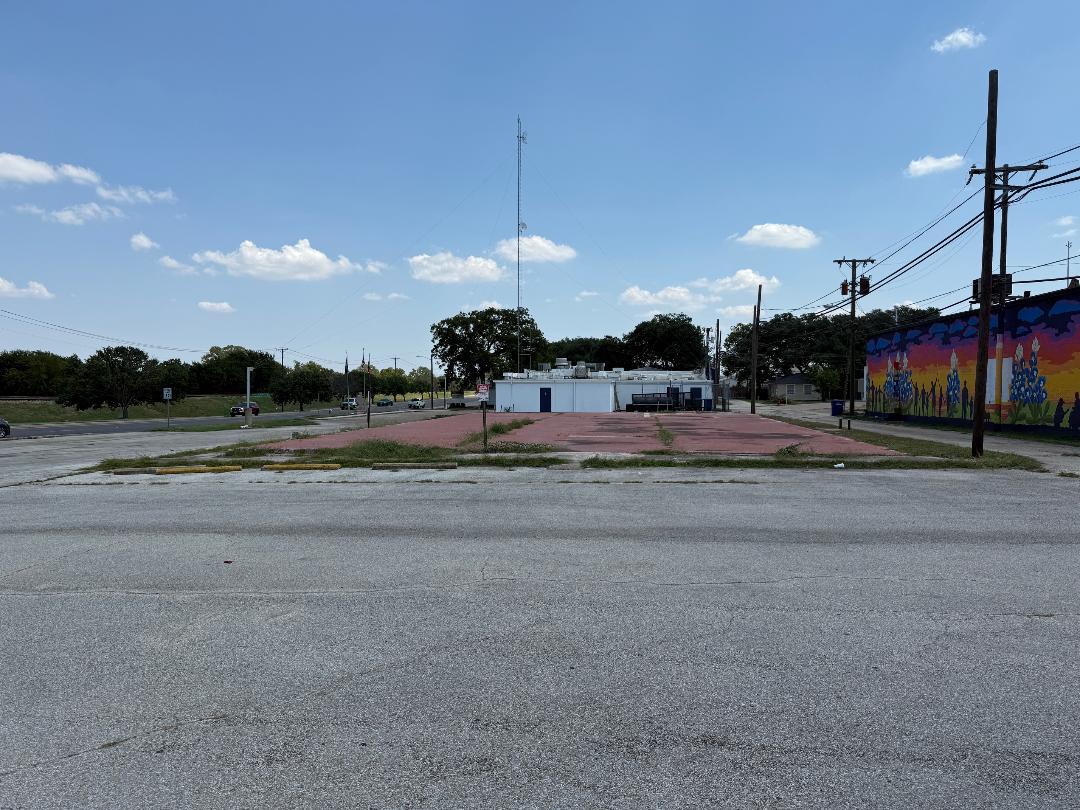 View of asphalt road featuring sidewalks and curbs