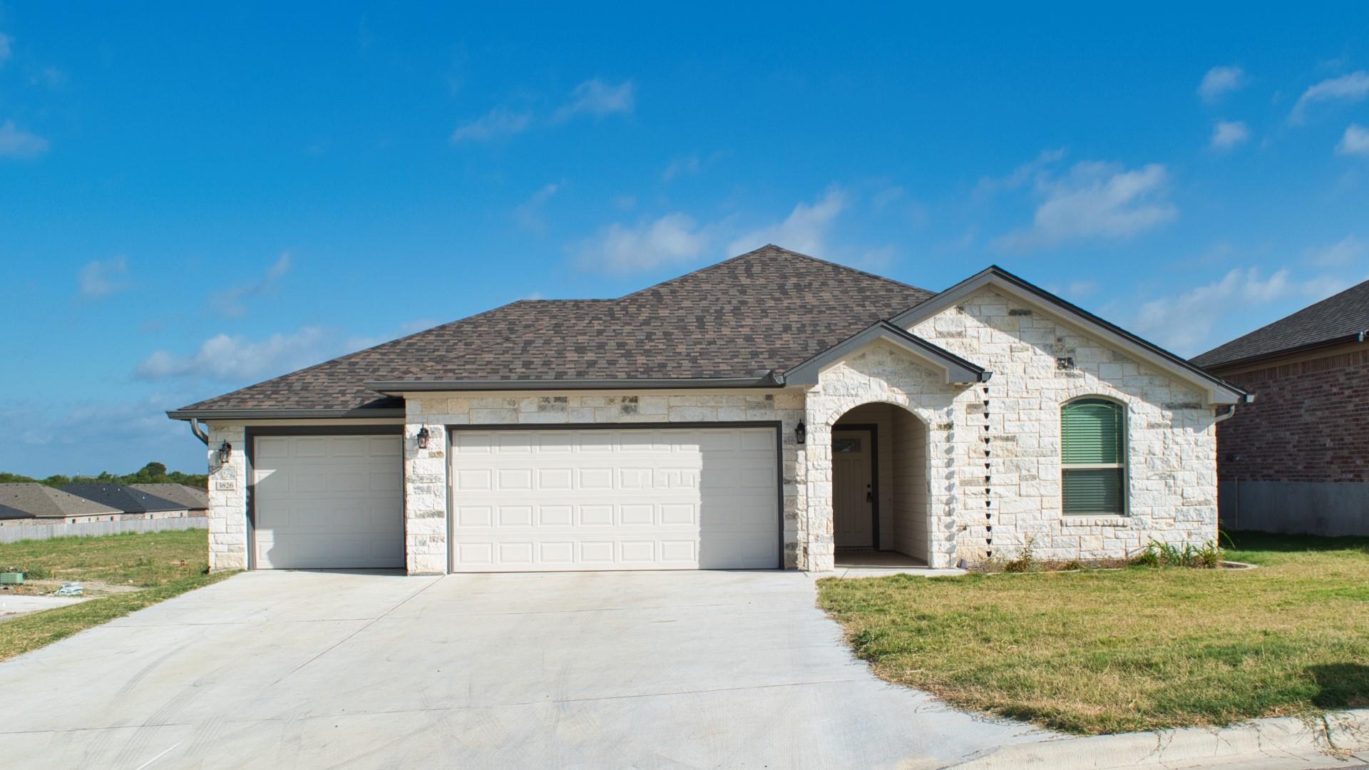 French country home with stone siding, a front ya