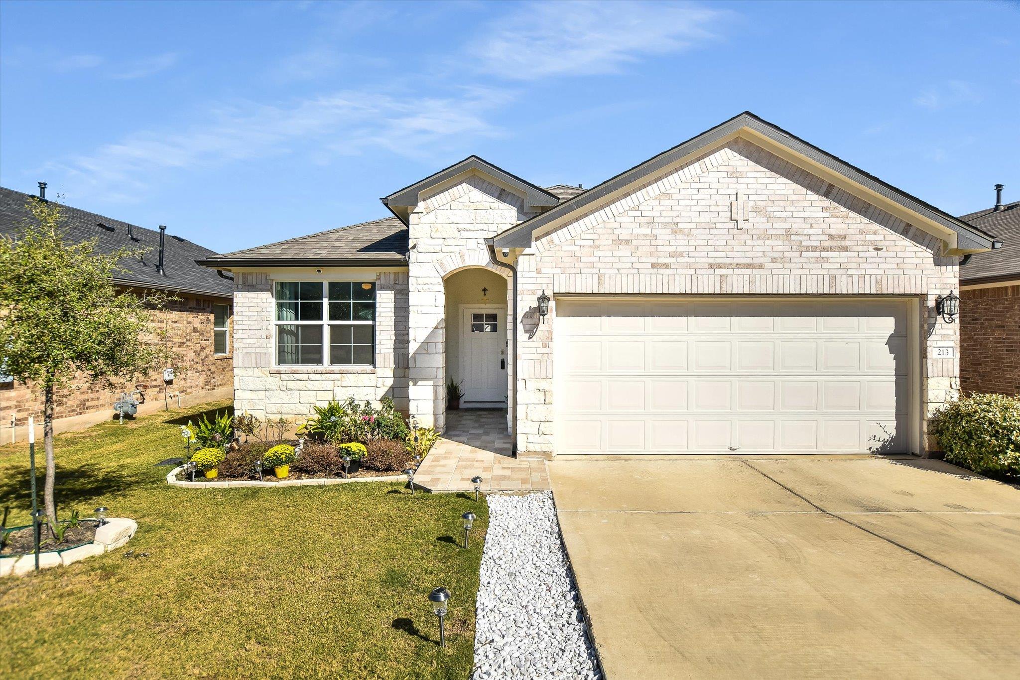French country home with stone siding, driveway, 