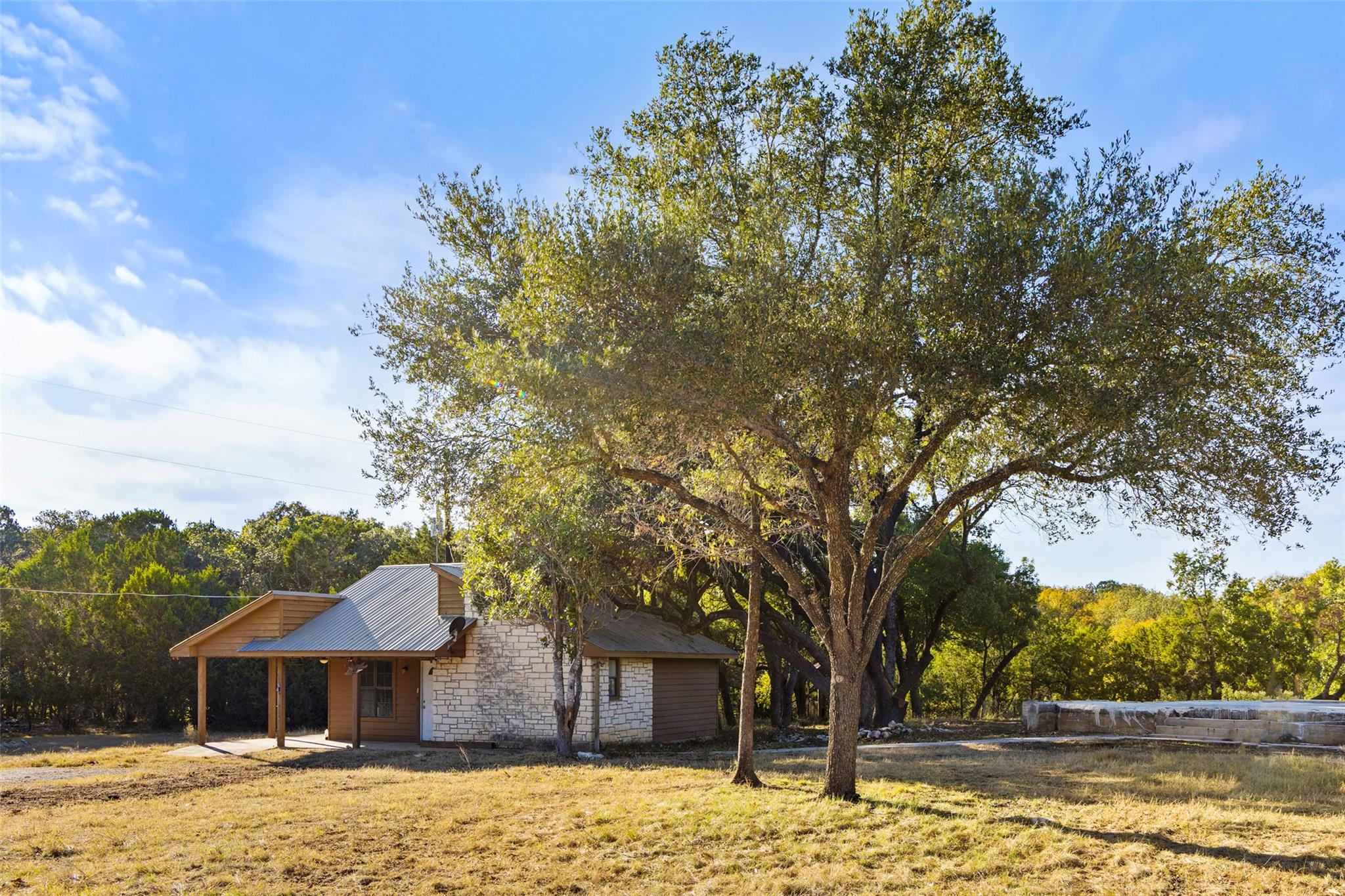 View of home's exterior with stone siding, a pati