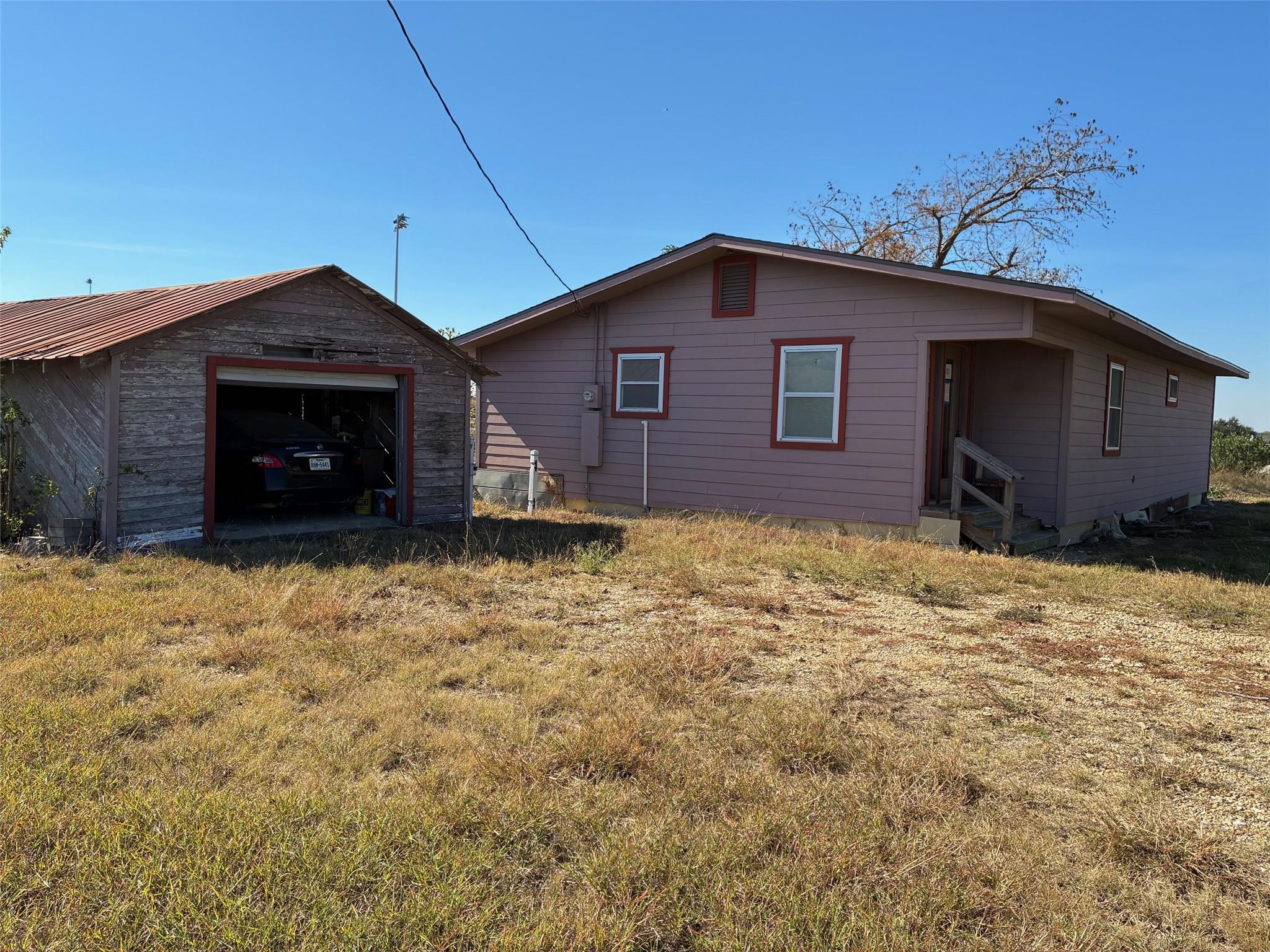 Back of property with an outbuilding and a yard