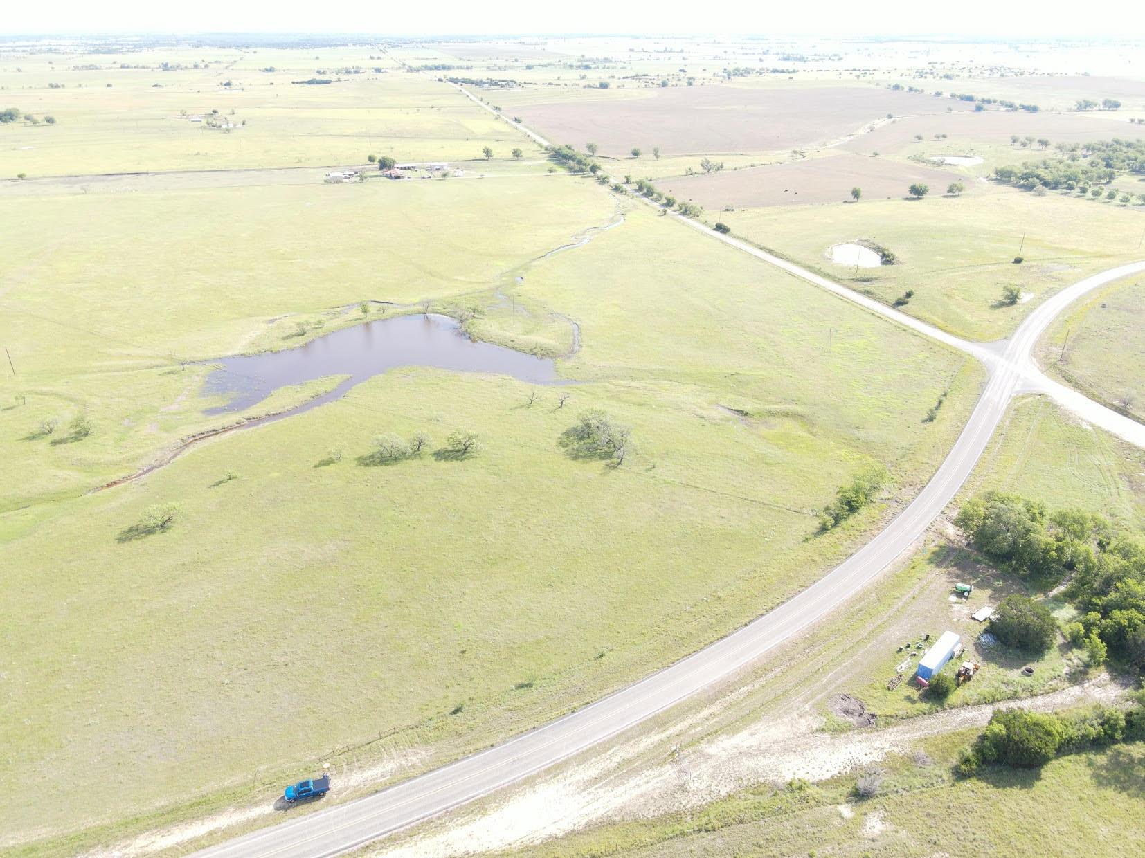 Vast green acreage featuring a tranquil pond, bor