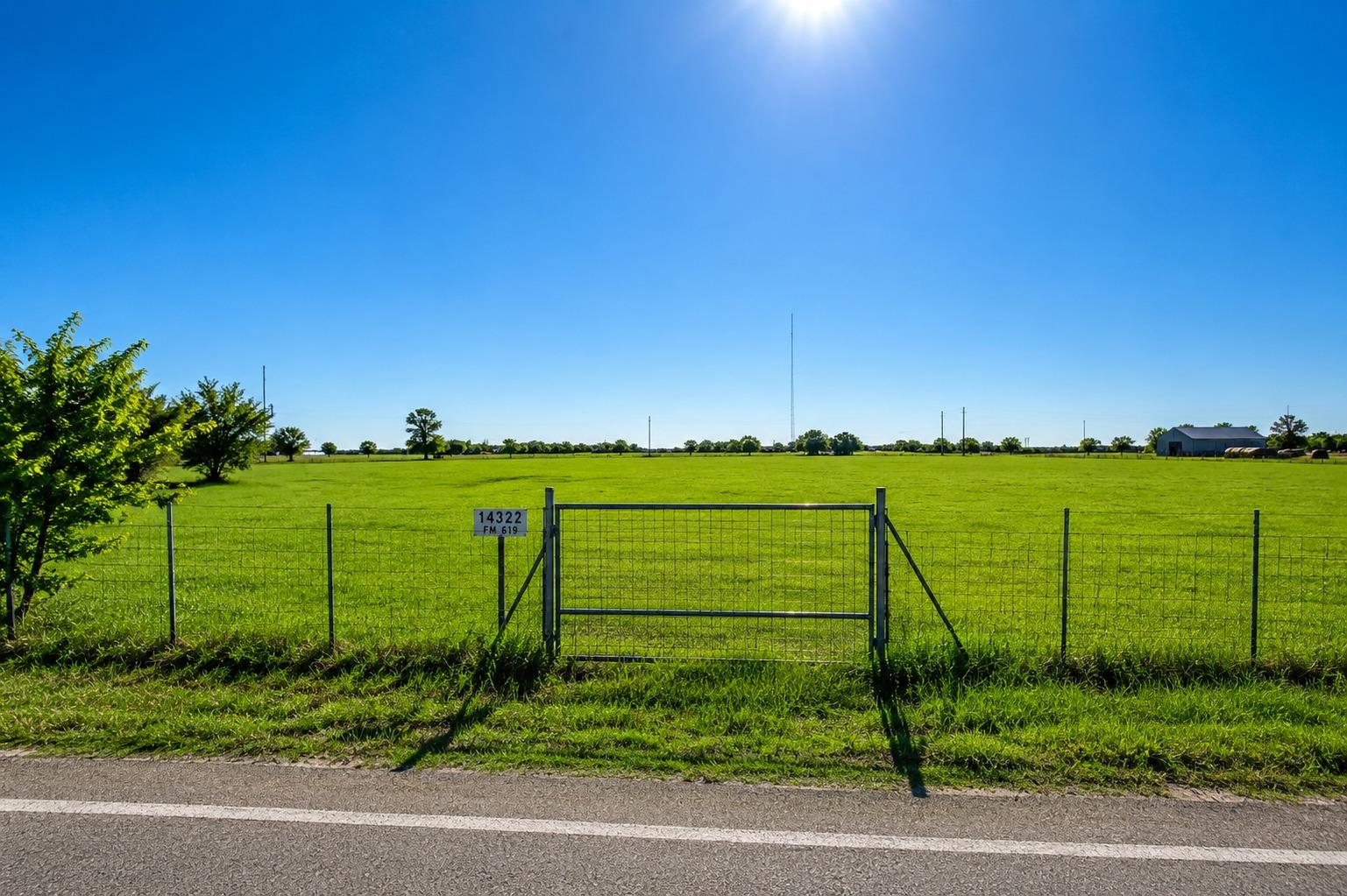 Fenced green pastureland stretches out under a cl
