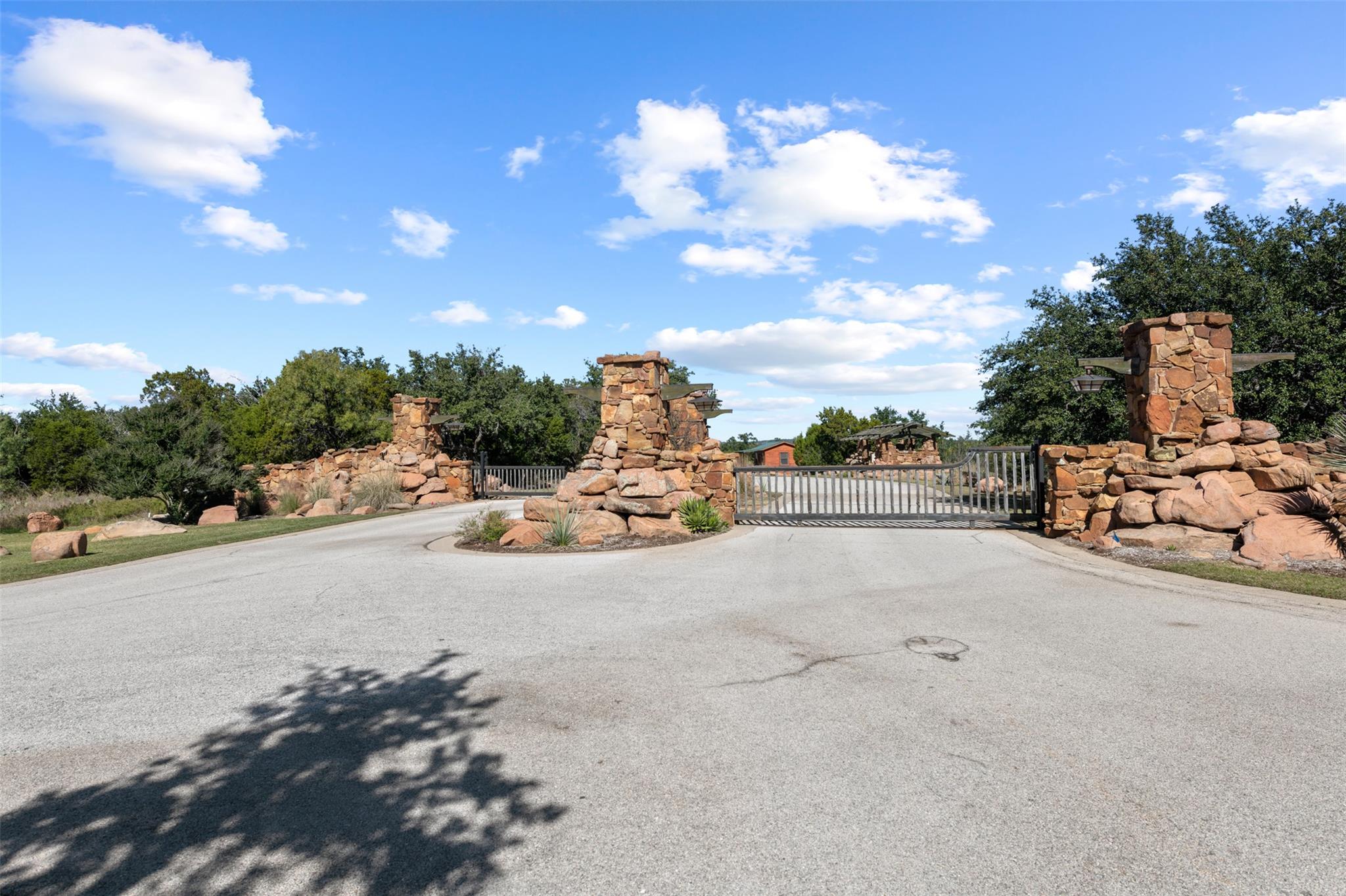 View of asphalt street with a gate and a gated en