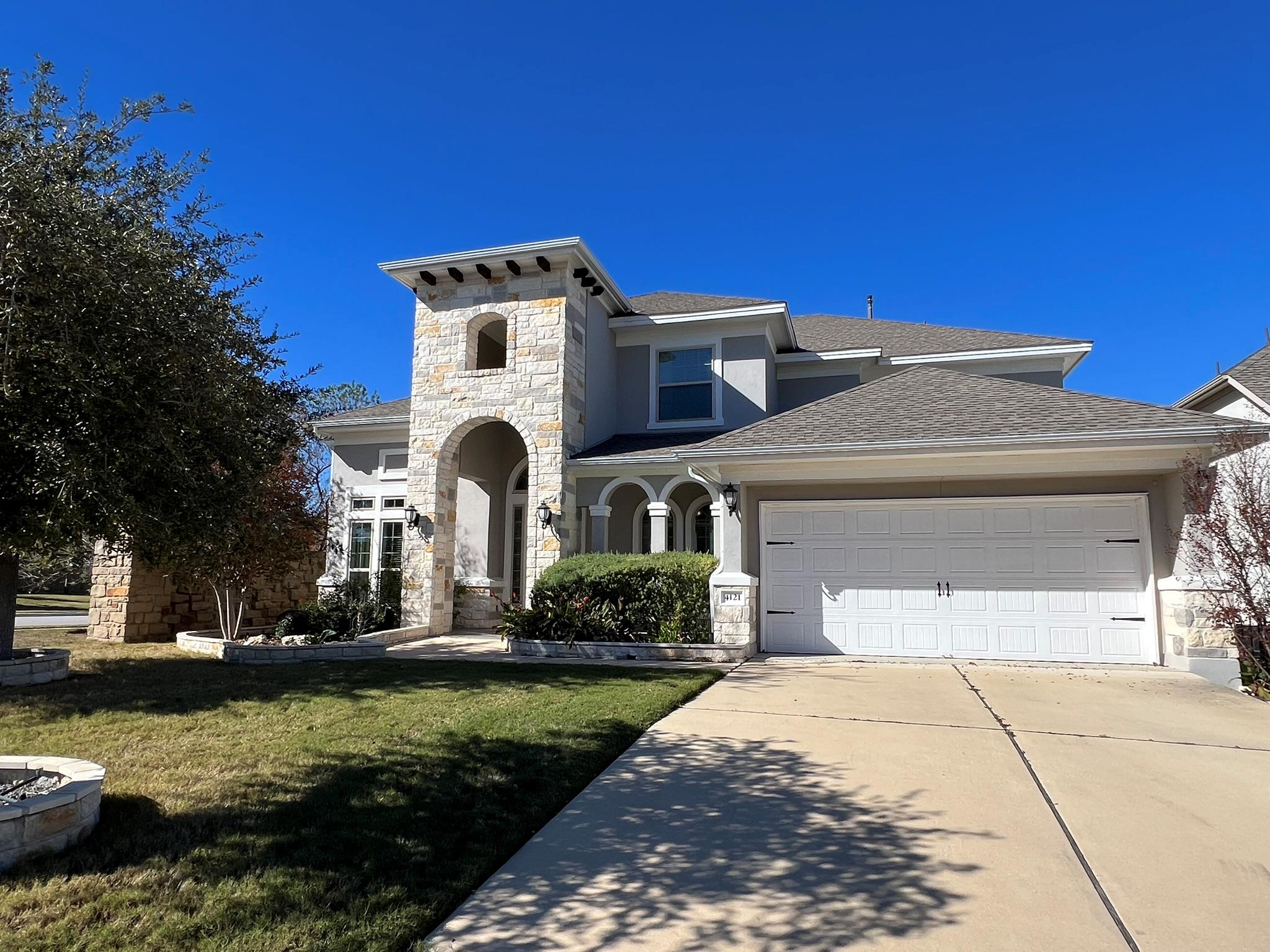 View of front of house with stone siding, stucco 