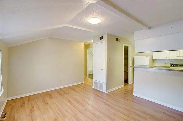 Empty room featuring lofted ceiling, a textured c