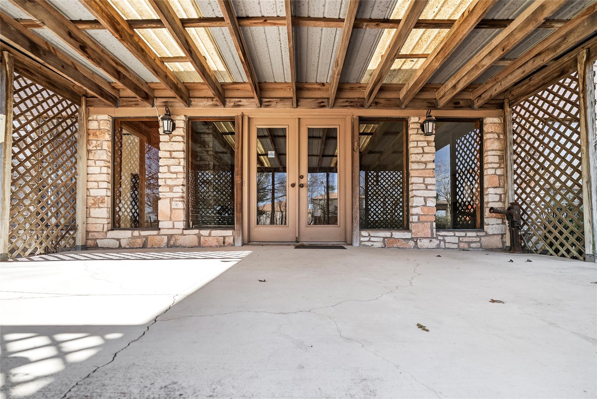View of exterior entry with stone siding, a patio