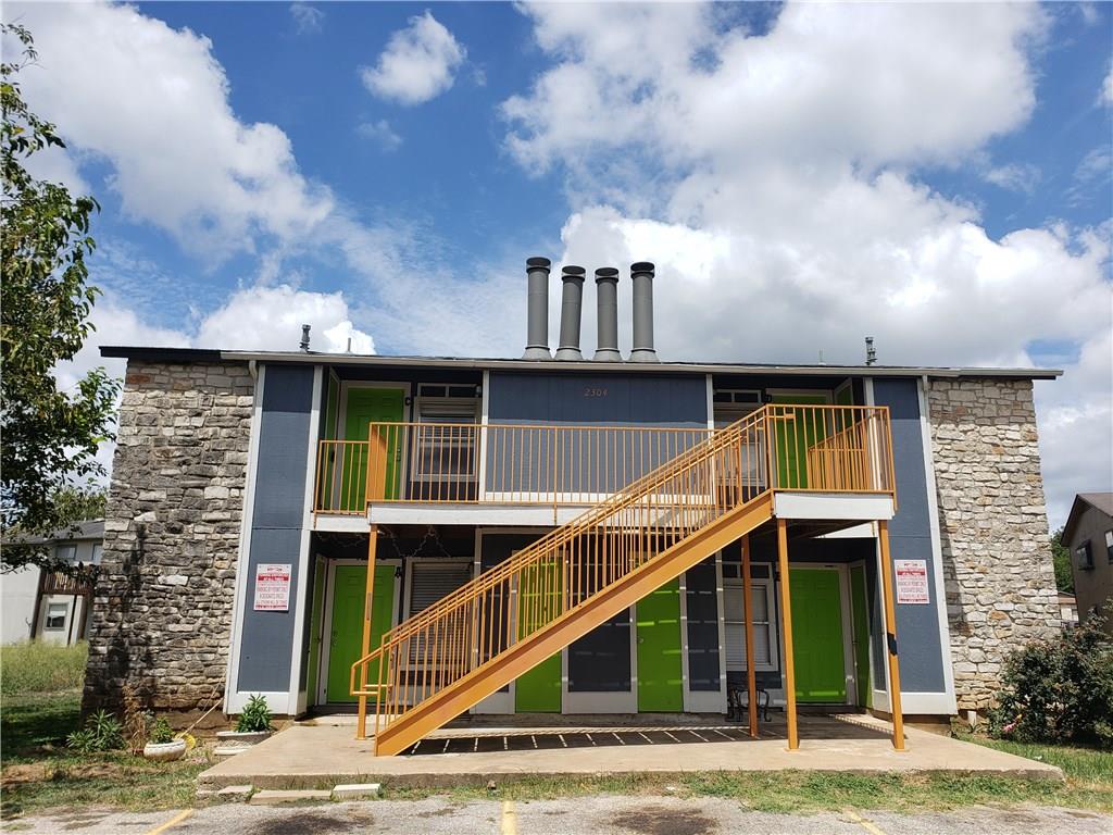 Rear view of property featuring stone siding, sta