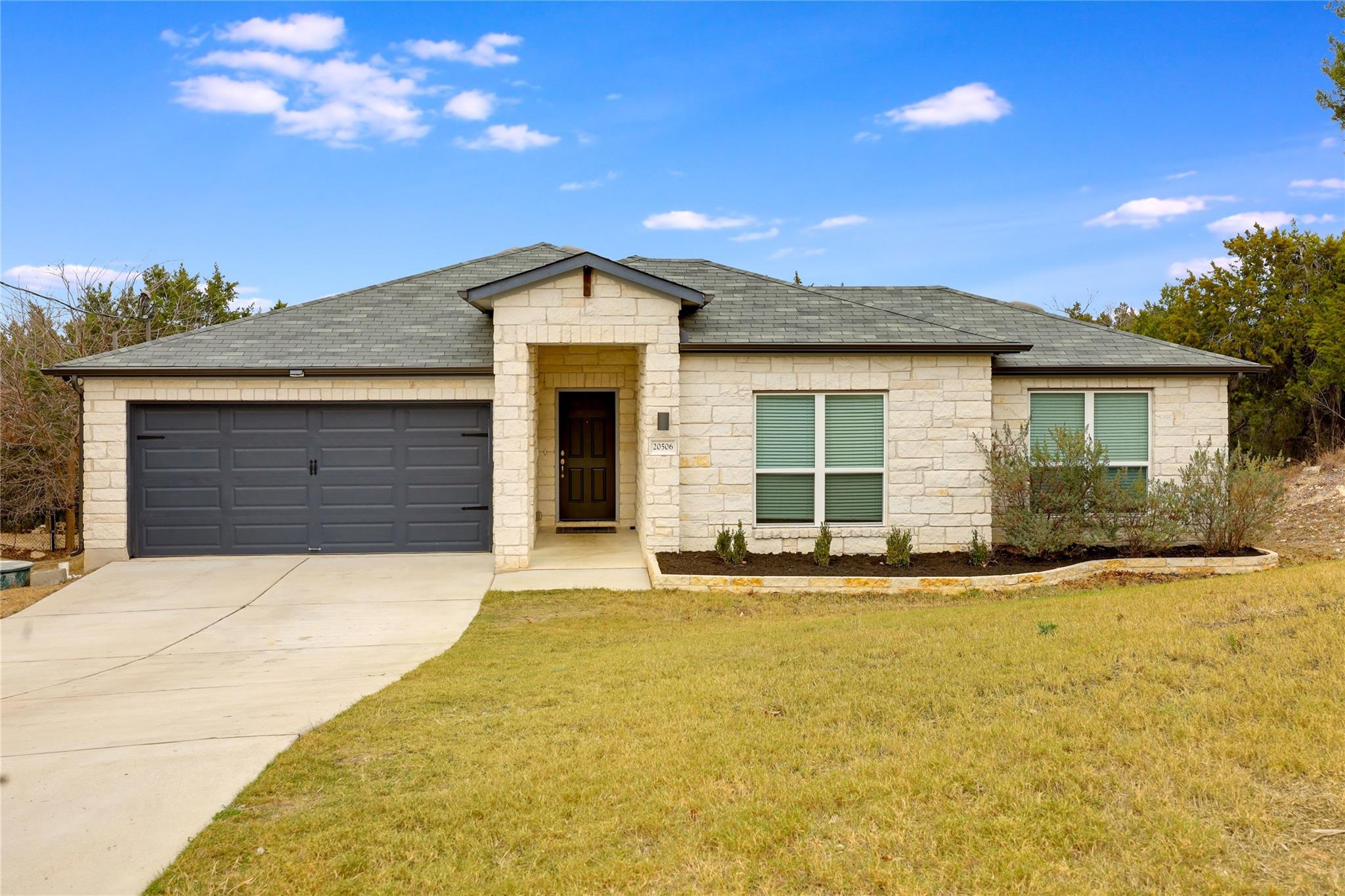 Ranch-style home featuring stone siding, roof wit