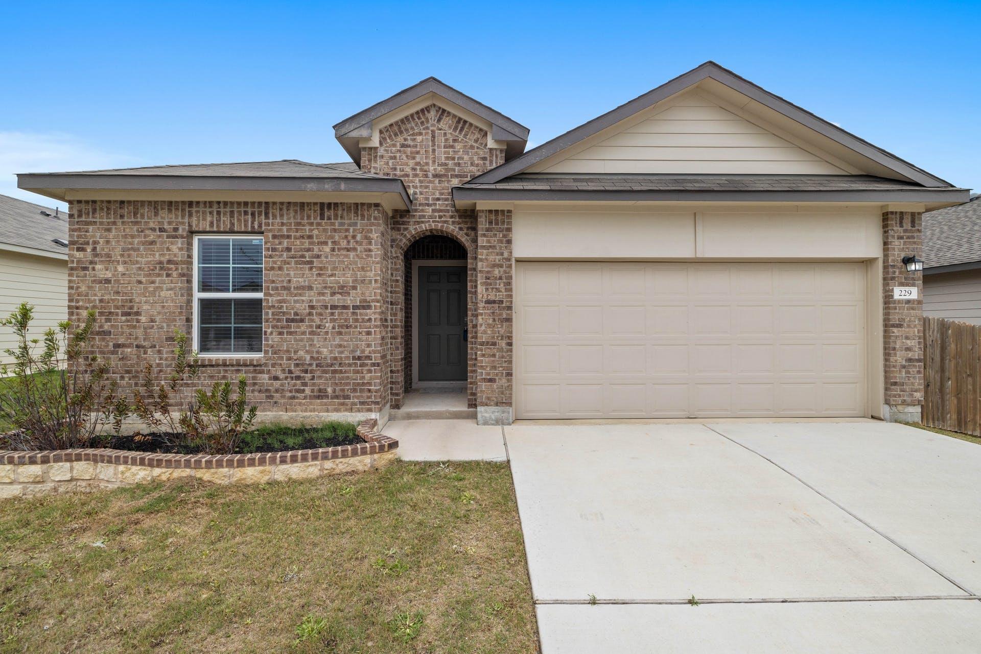 View of front facade featuring driveway, brick si