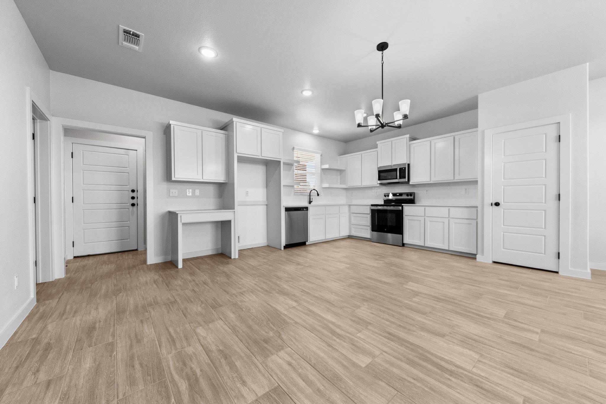 Kitchen with white cabinets, appliances with stai