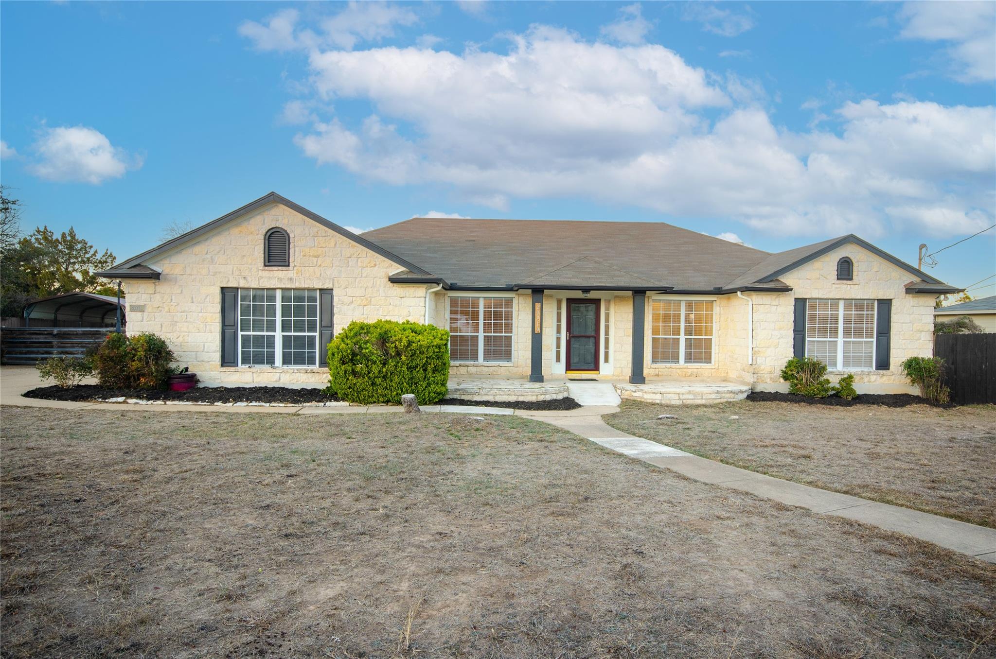 Ranch-style house with stone siding and covered p