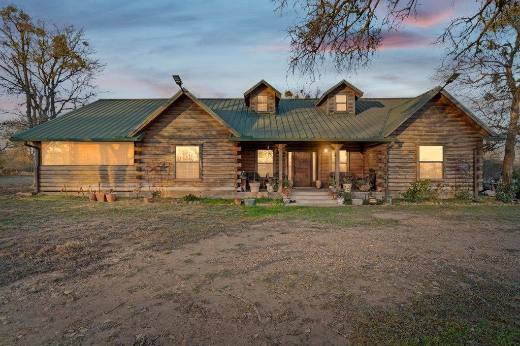 Back of house featuring covered porch, a metal ro