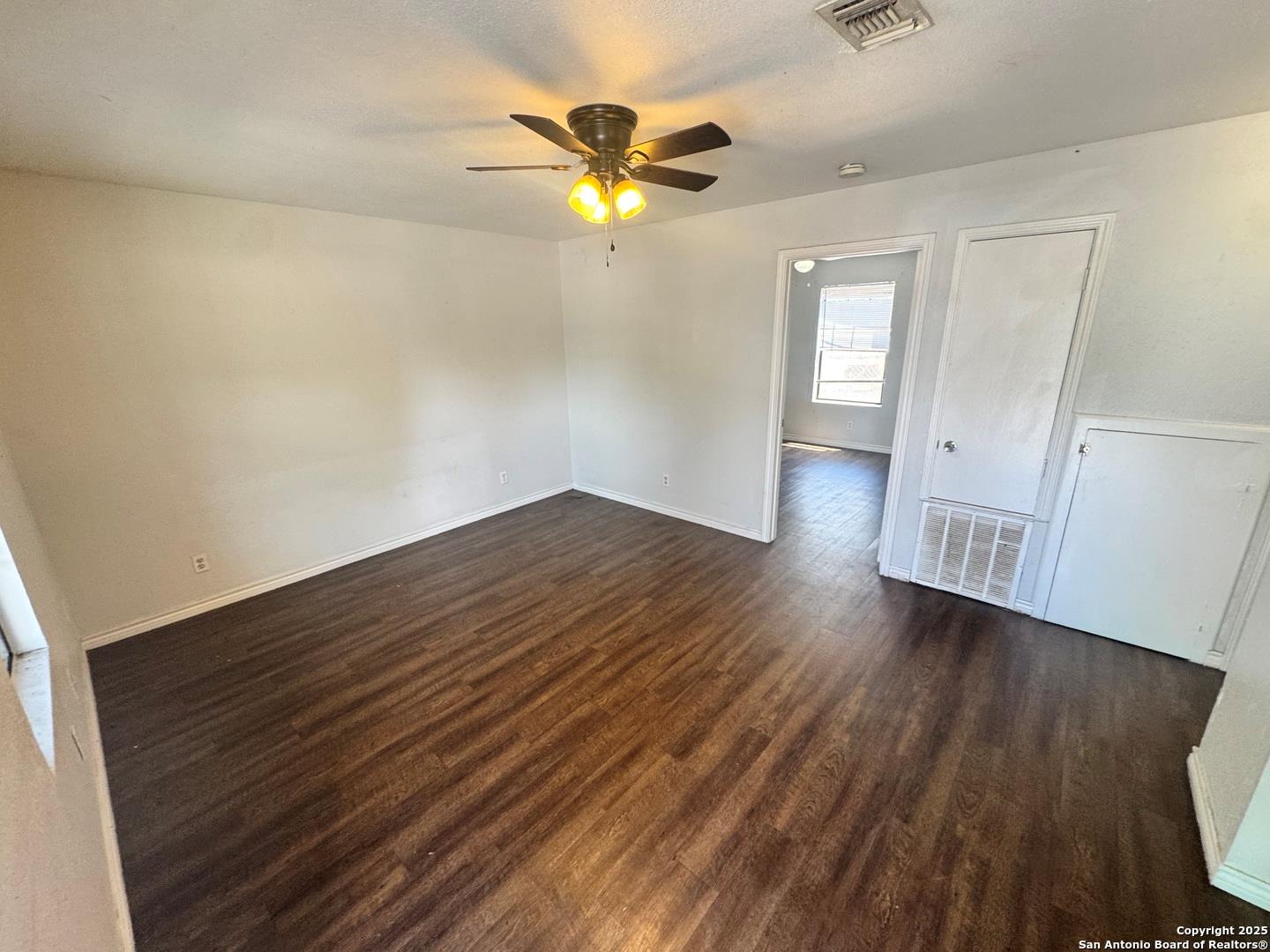 Empty room with ceiling fan and dark wood-type fl