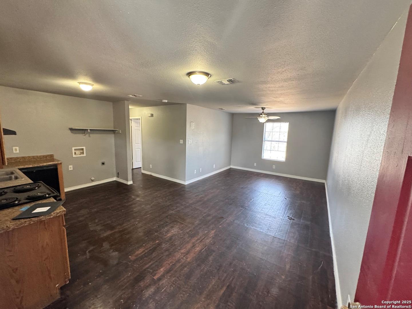 Unfurnished living room with dark wood-style floo