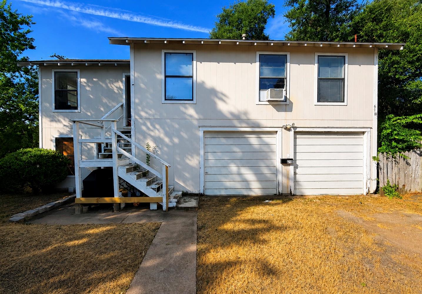 Two garage doors offer ample parking beneath a tw