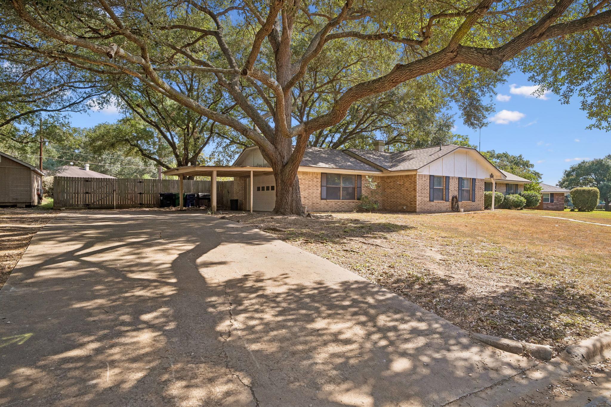 Mature shade trees frame this classic brick singl