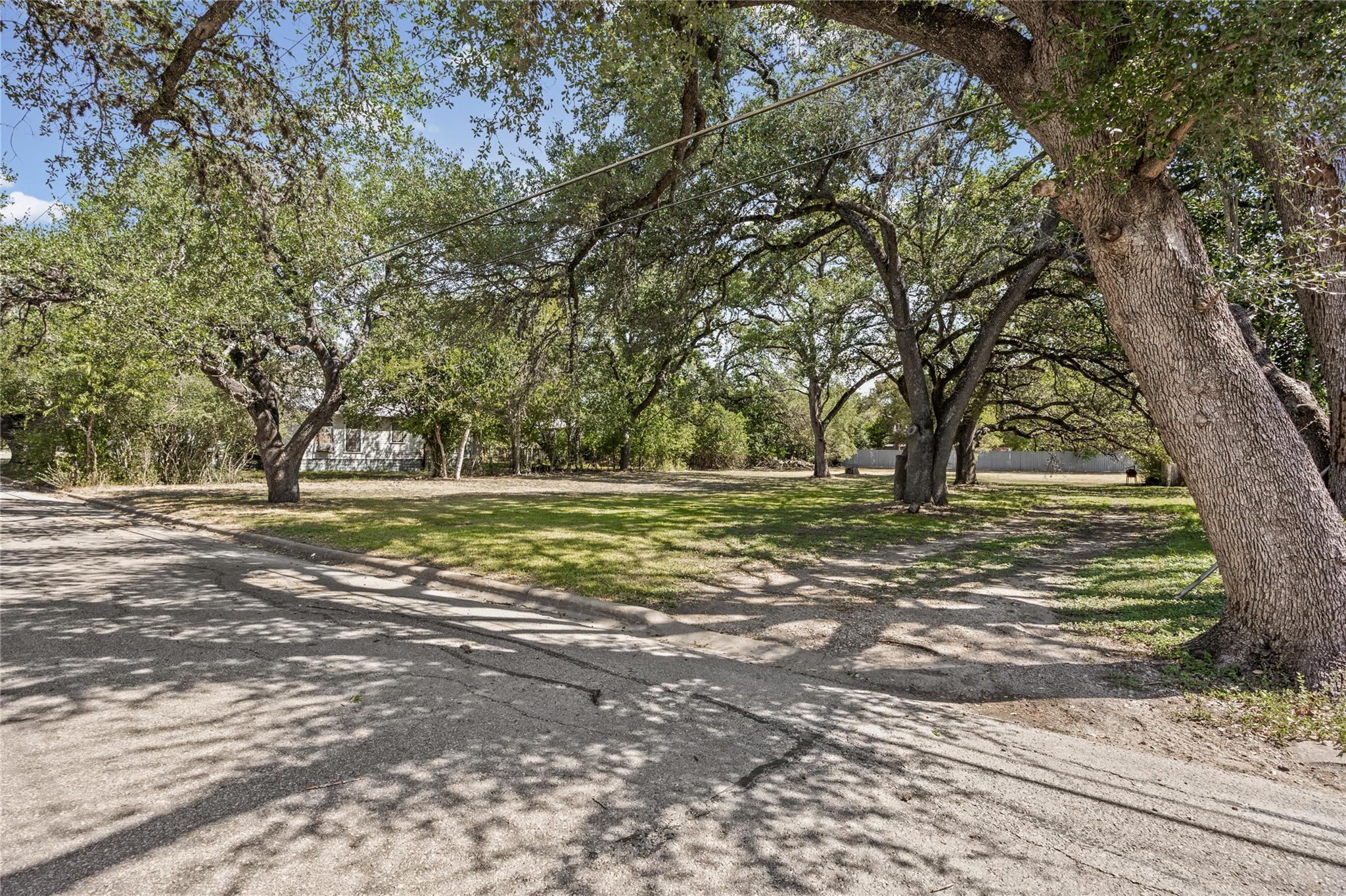 Mature shade trees frame a spacious lawn along a 