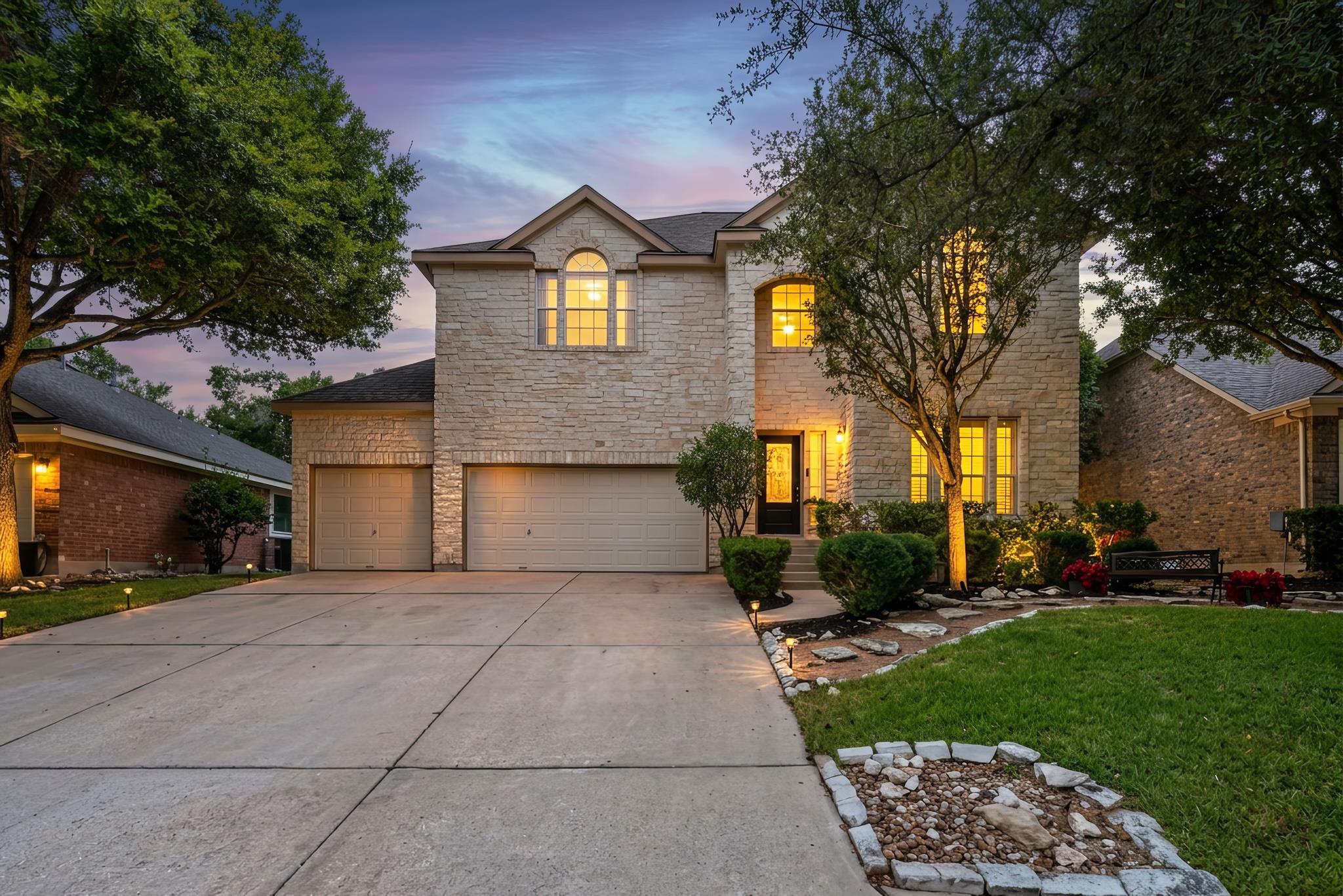 A stone facade and concrete driveway lead to the 