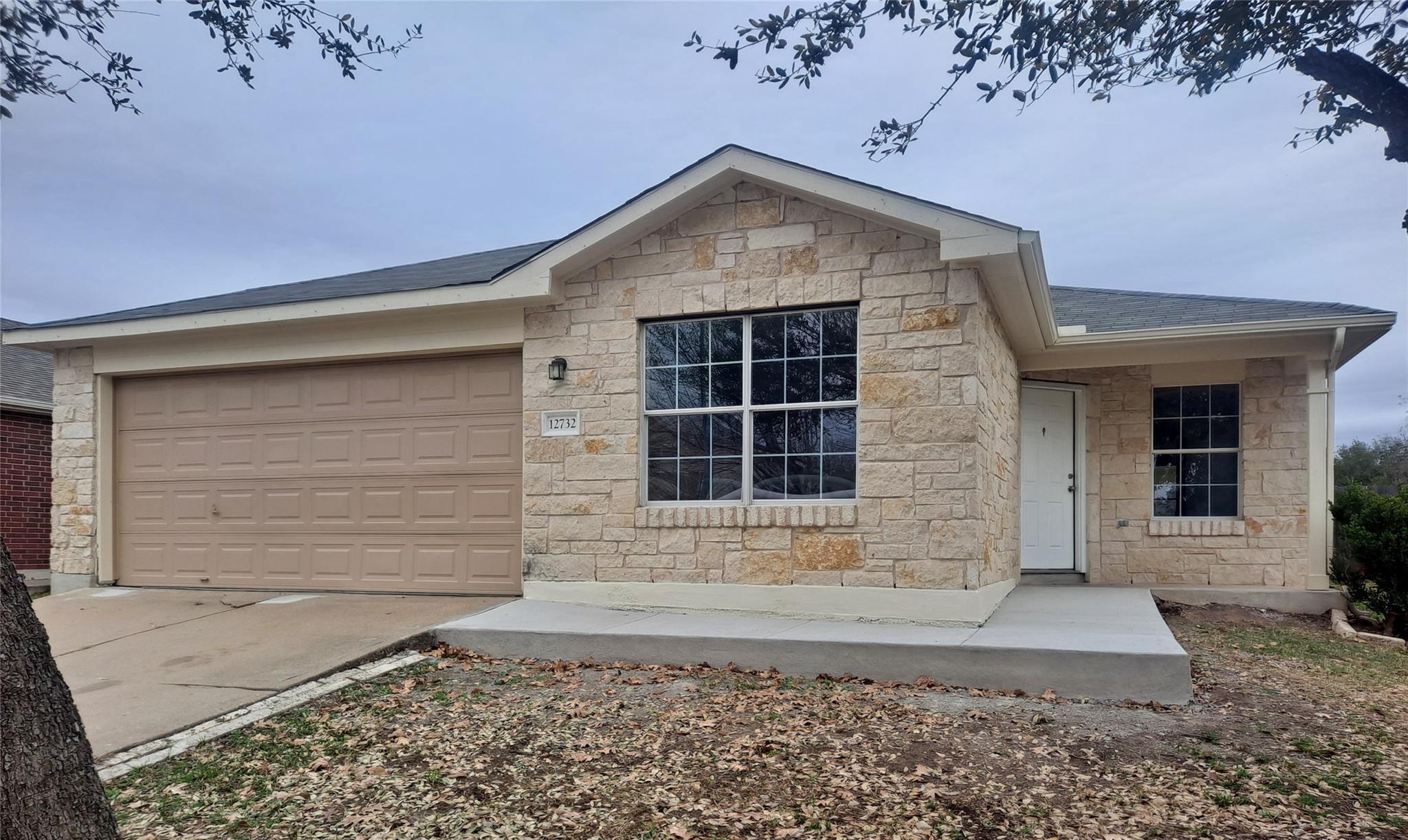 Ranch-style home with stone siding, a garage, con