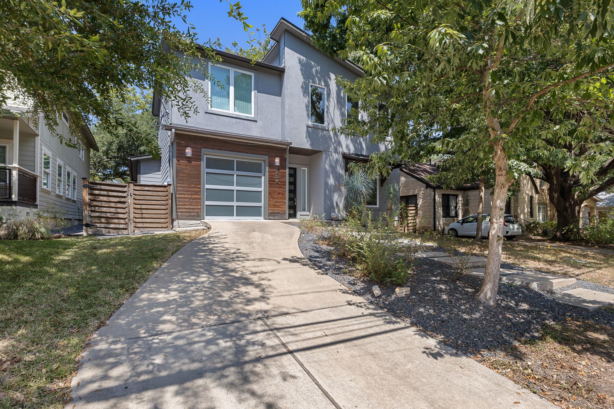 Mature trees frame the sleek exterior of this con