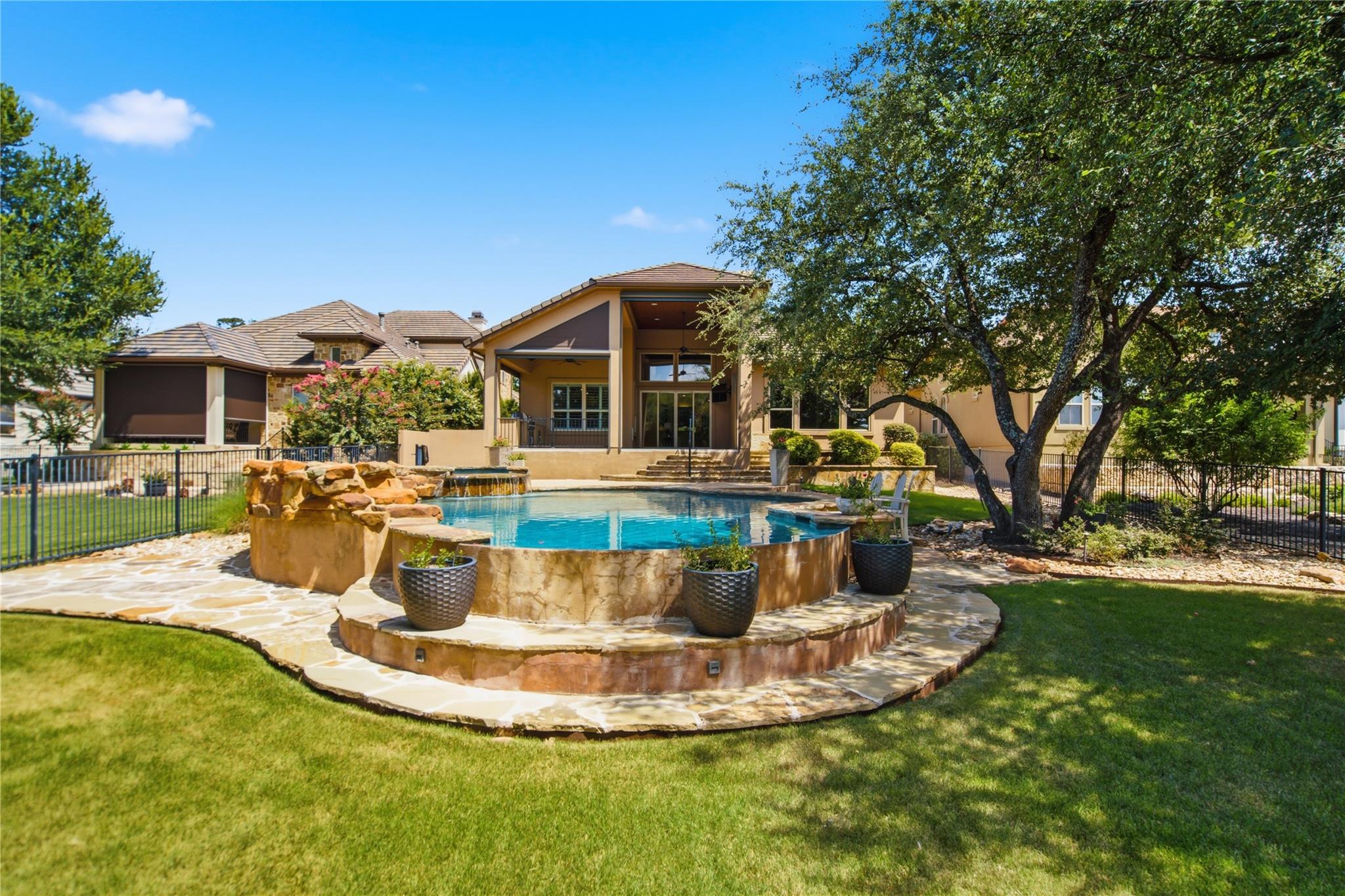 An inviting pool and spa beckon in a verdant back