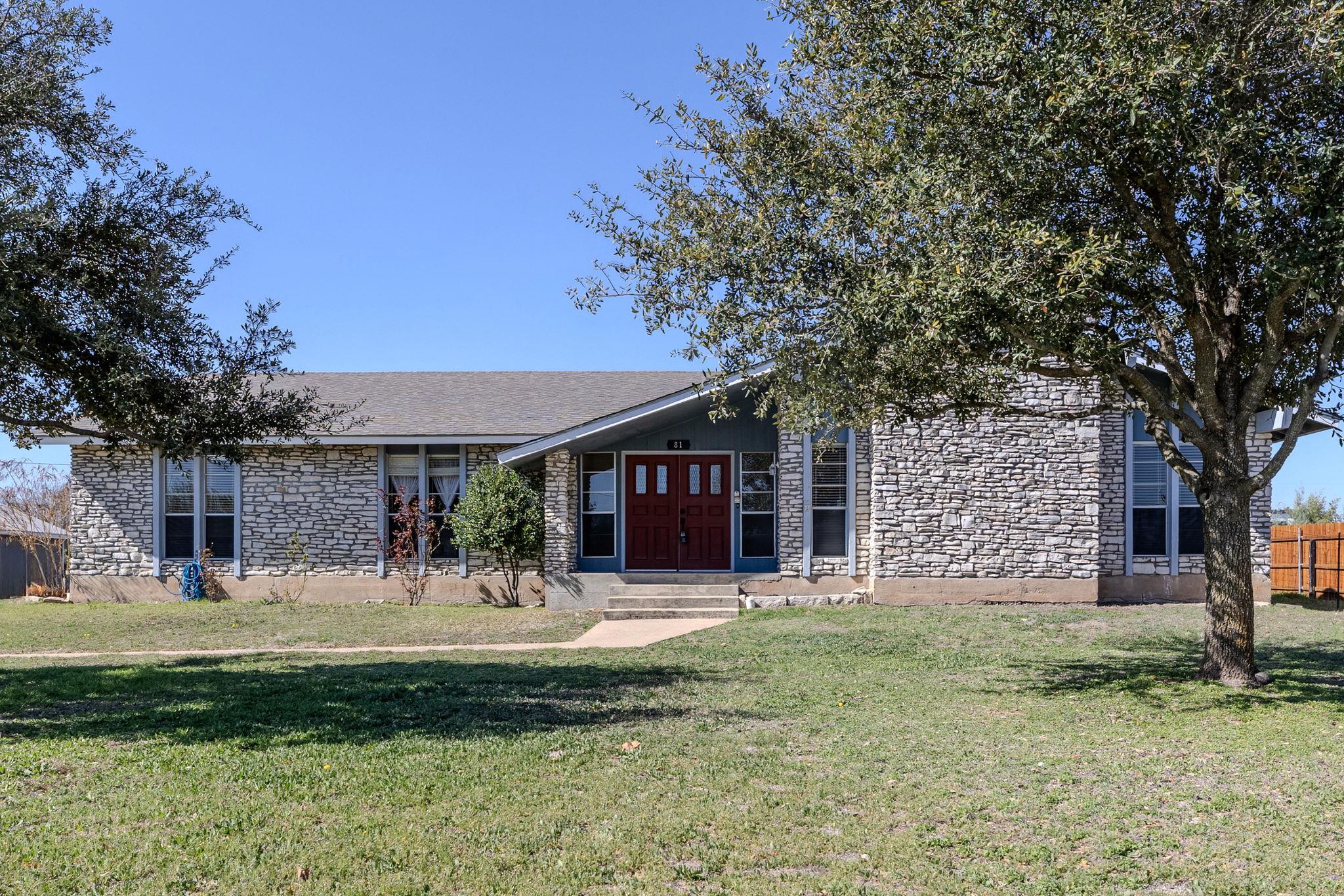 View of front facade with stone siding, a front y