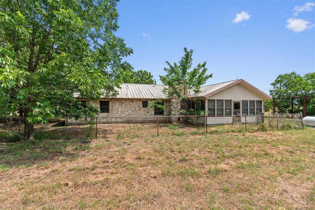 Back of property with a sunroom, stone siding, an