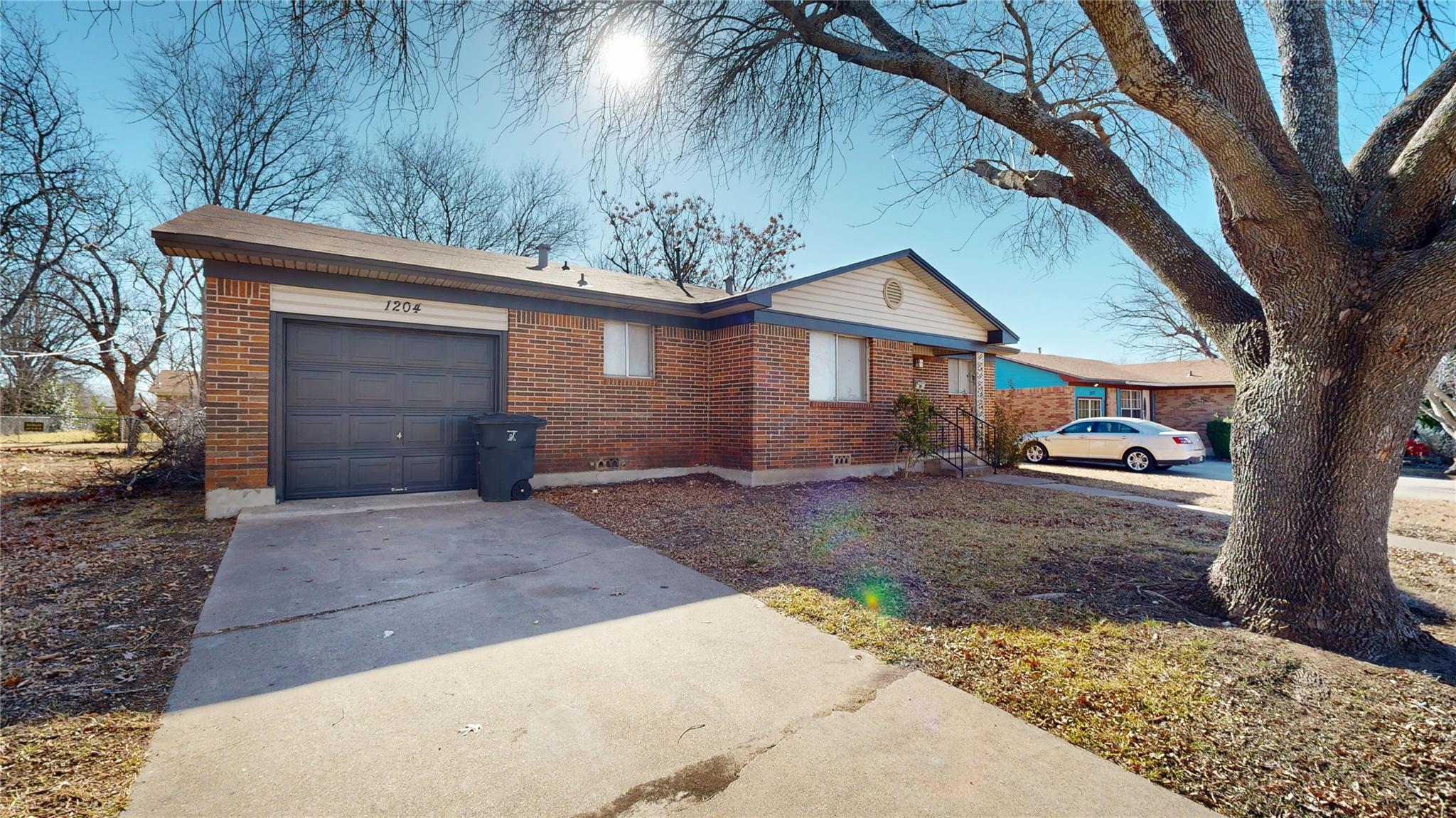 Ranch-style home with a garage, driveway, and bri