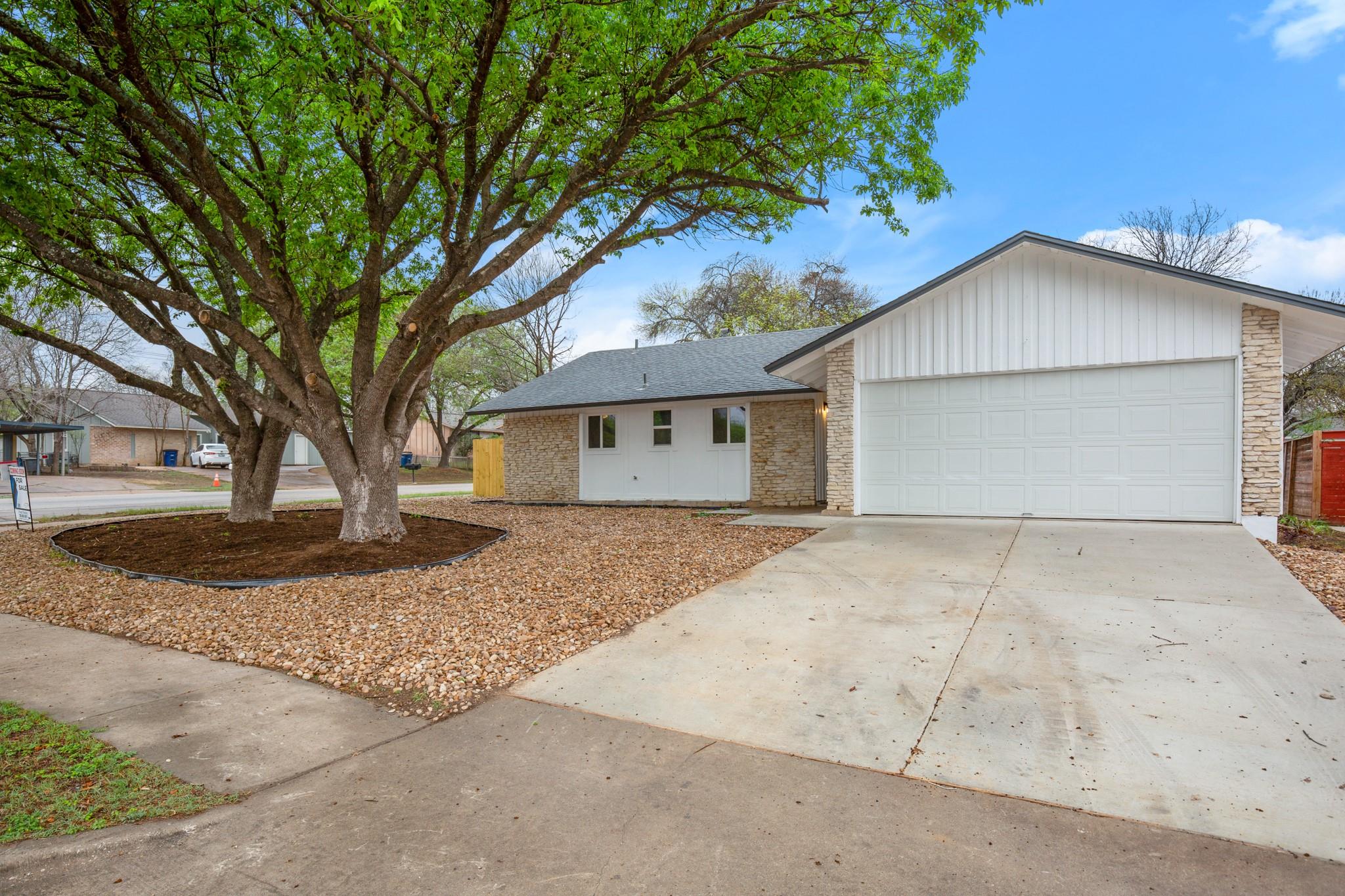 View of front facade featuring driveway and a gar