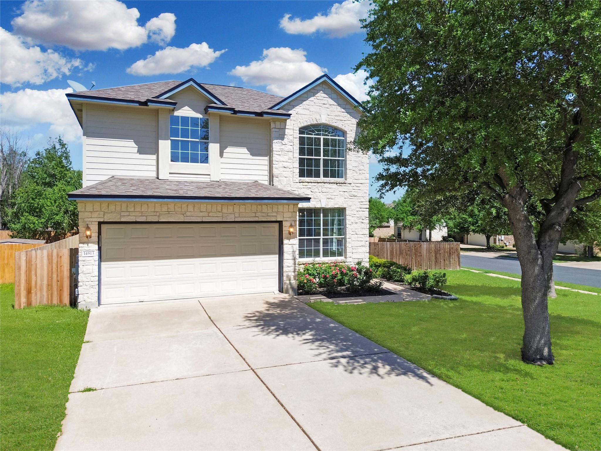 Traditional home with stone siding, driveway, a s