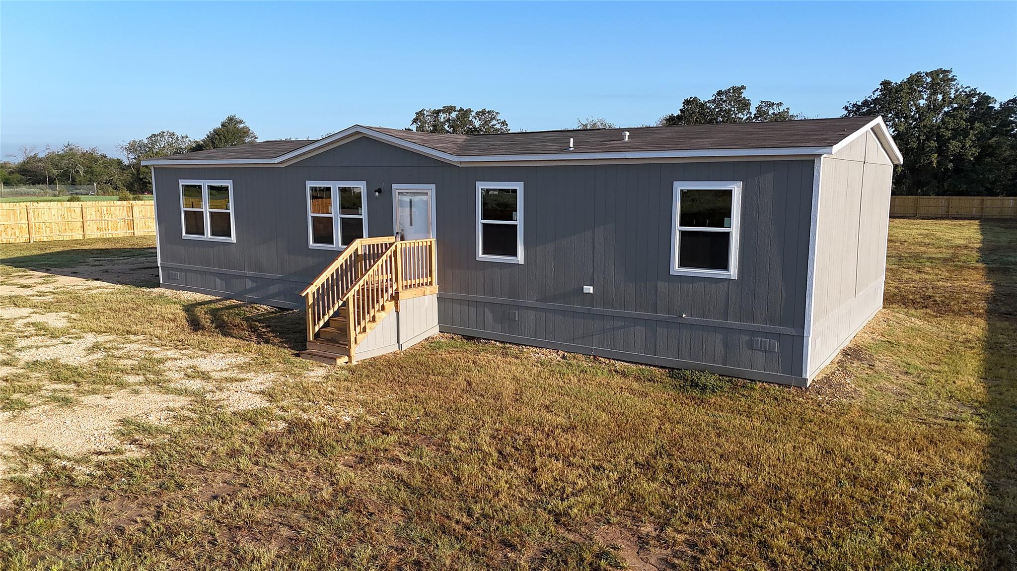 A modern manufactured home stands on a spacious g