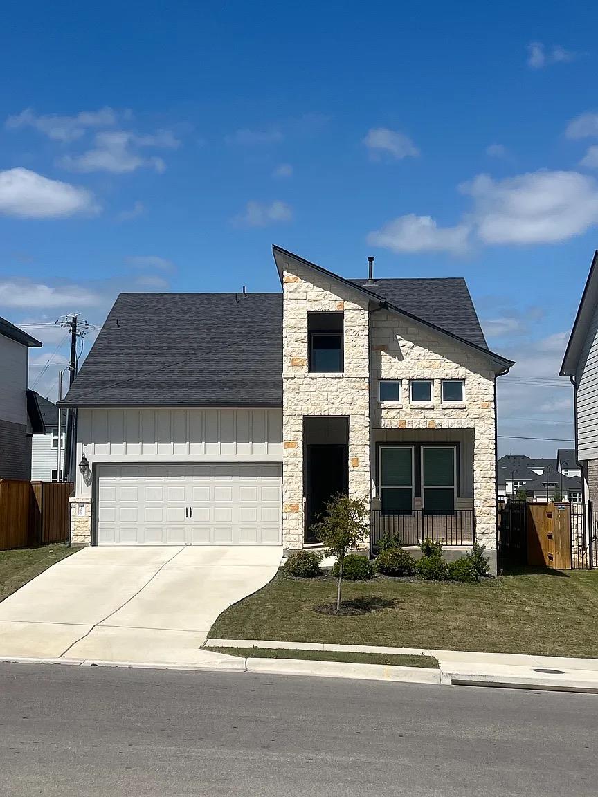 View of front facade with stone siding, a garage,