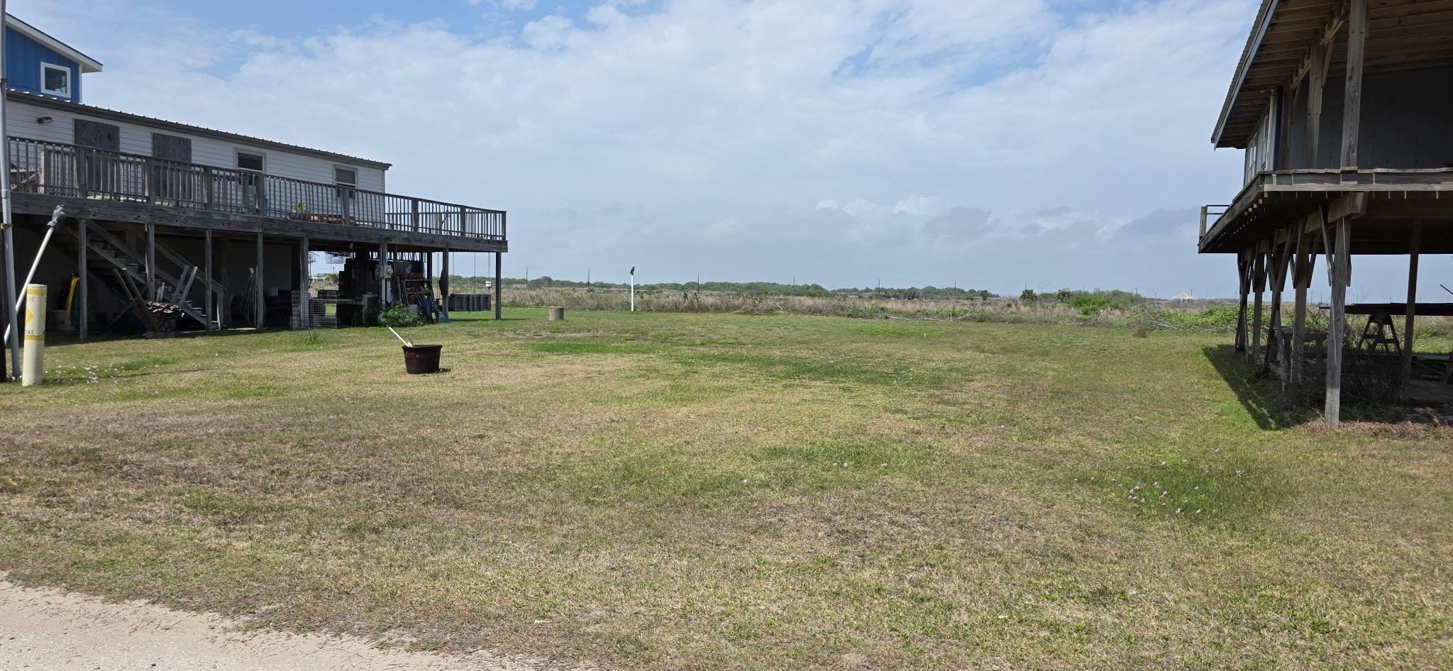 View of grassy yard with a deck and stairs